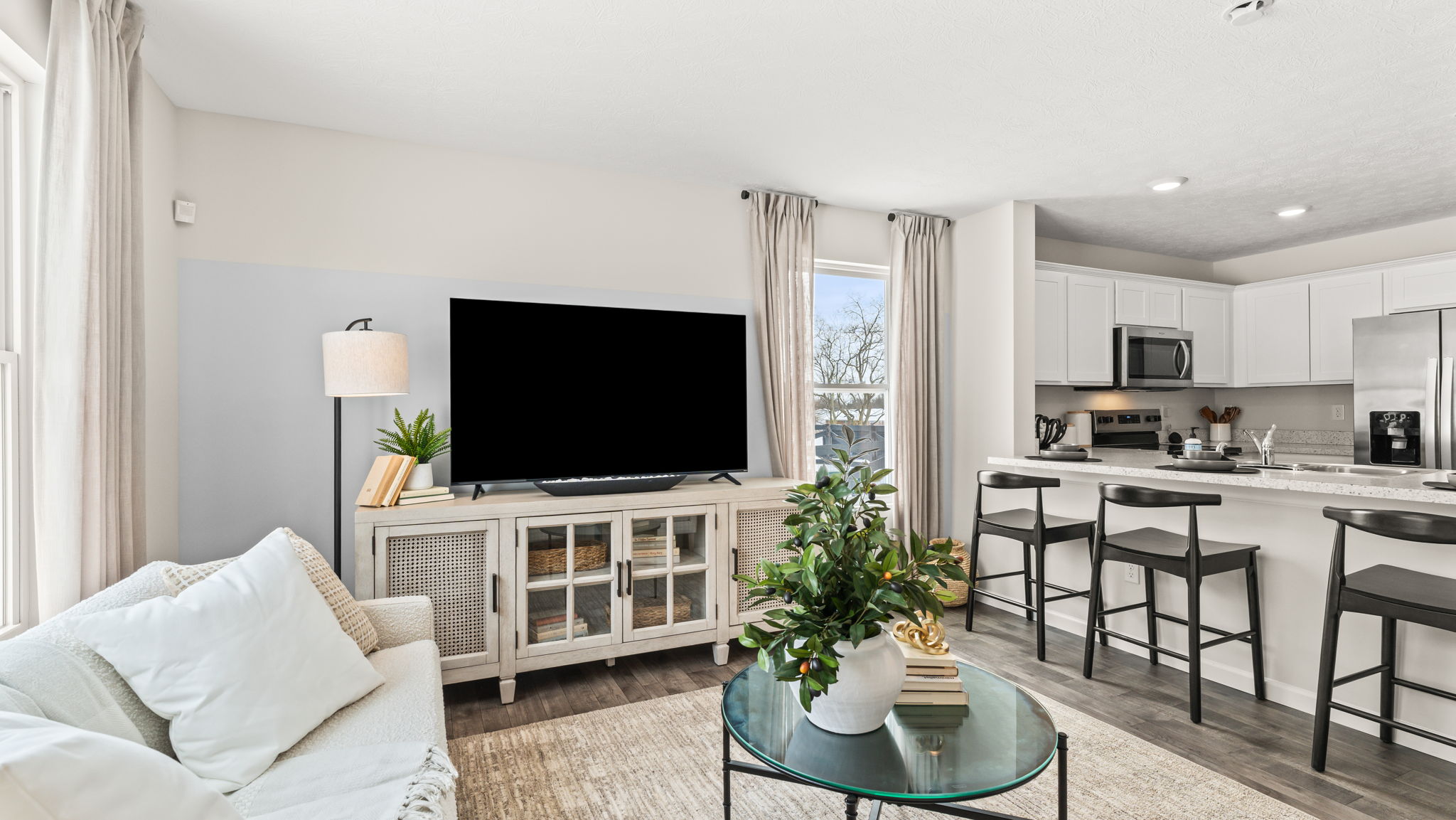 wide perspective image of a comfortable townhome living and kitchen area with plenty natural light and green tones complimenting the wooden furniture