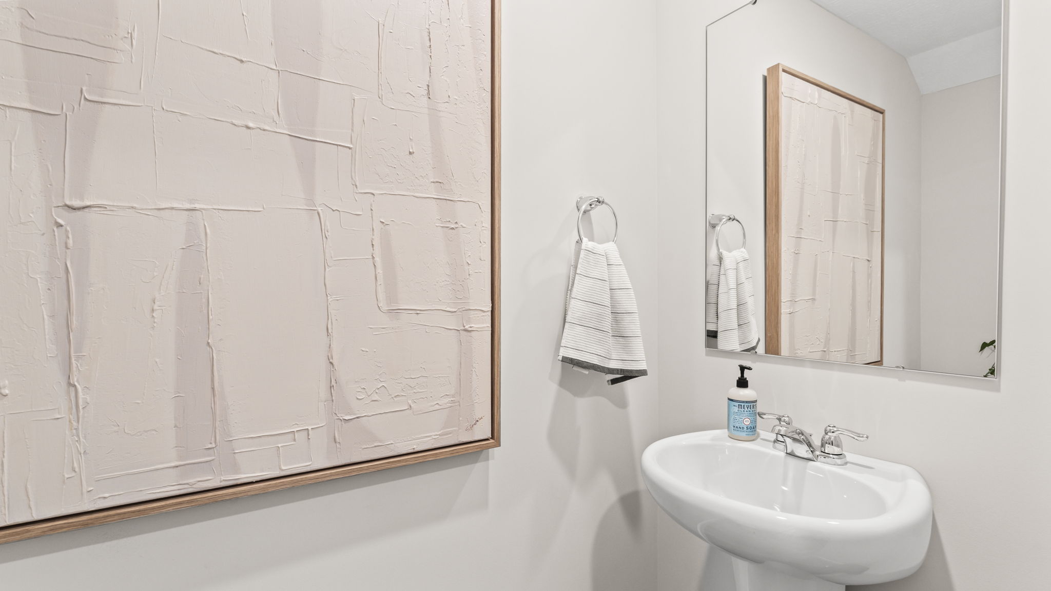 Closeup of powder room with white abstract paint, sink, and mirror