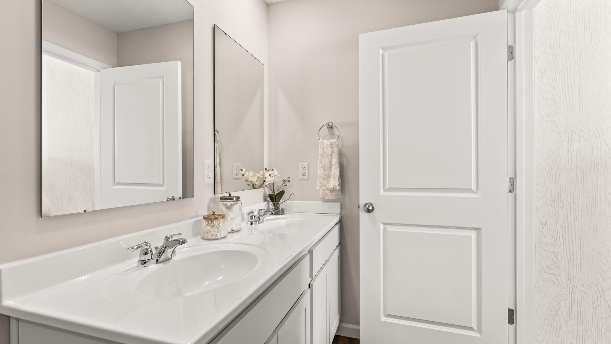 Closeup of white countertops of the double bowl vanity with two sinks and mirrors.