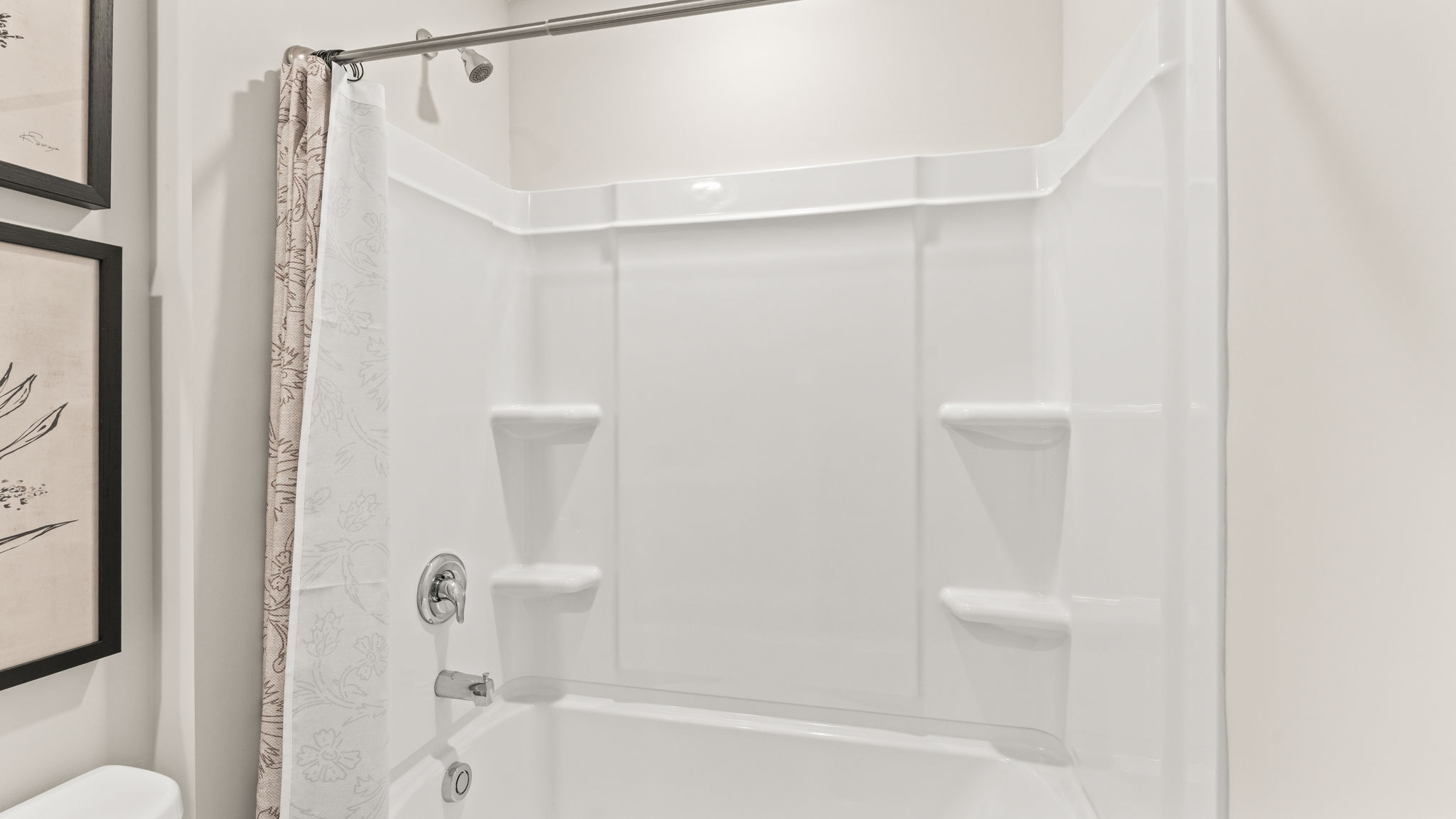 Closeup of bath/tub with brown patterned shower curtain and tiered shelving