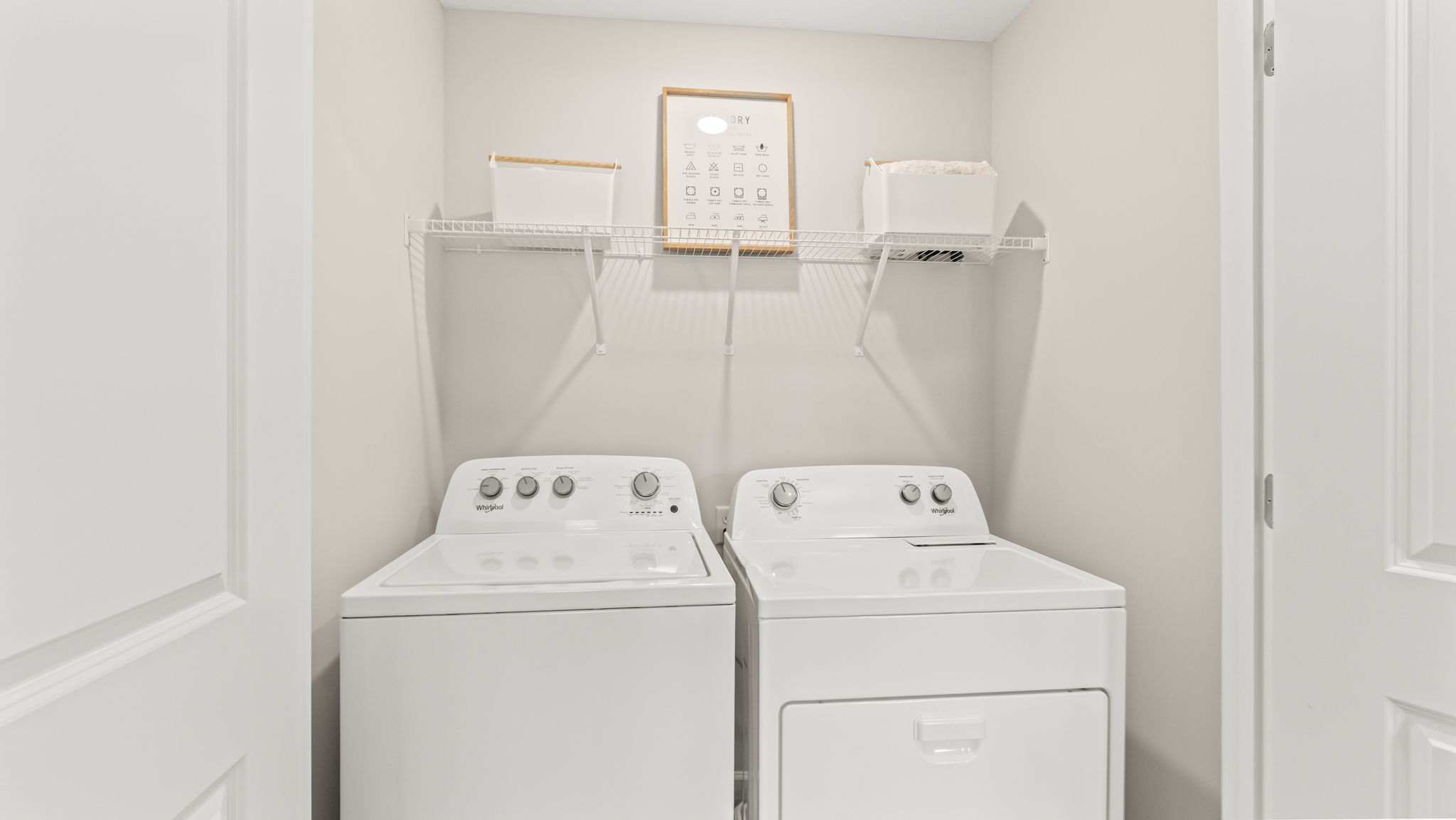 Laundry area with washer/dryer and wire rack shelving holding baskets and laundry tag display