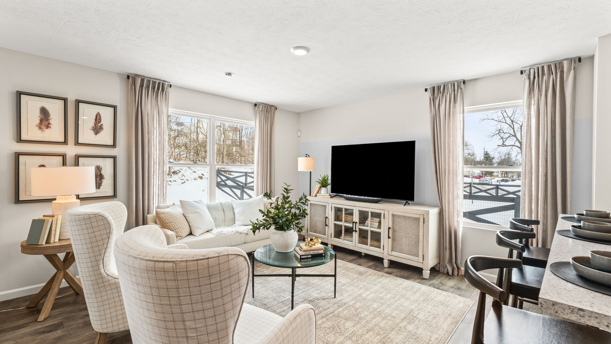 Modern cozy living room with soft white furniture accented by wood tones and a circular glass coffee table