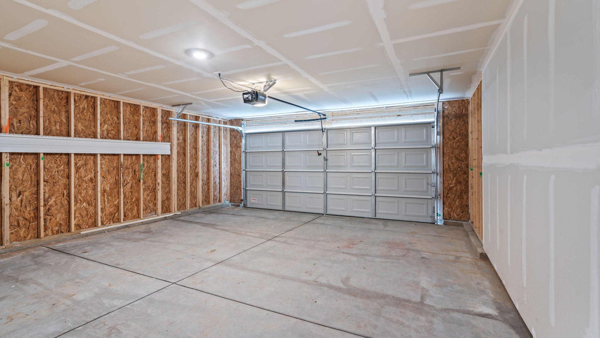 Two car garage with concrete flooring.