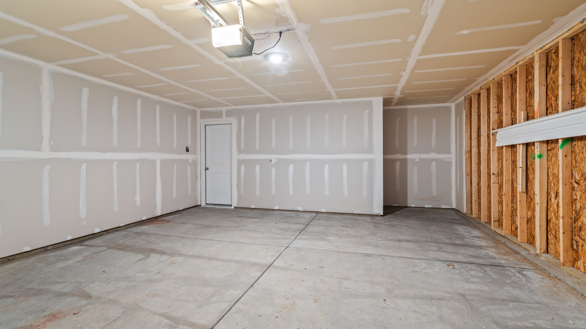 Two car garage with concrete flooring.
