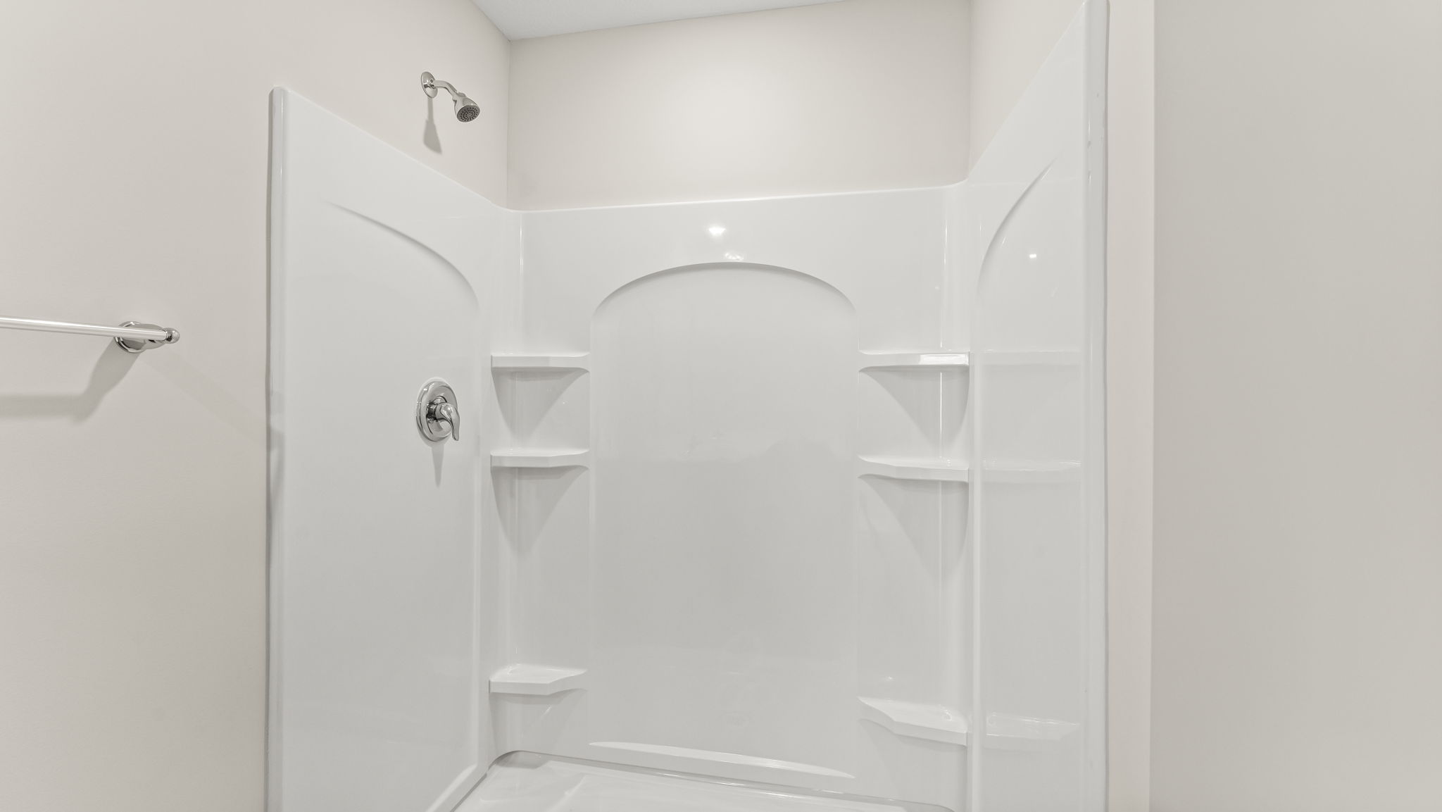 Spacious walk in shower with a tall shower head.