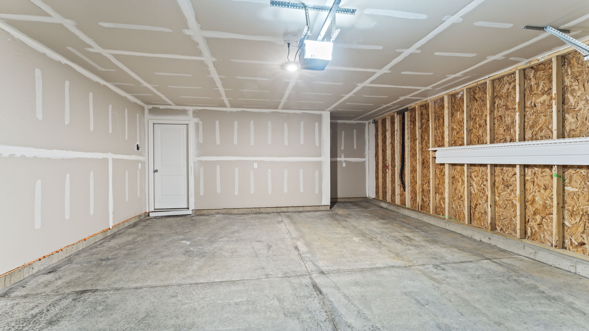 Two car garage with concrete flooring.