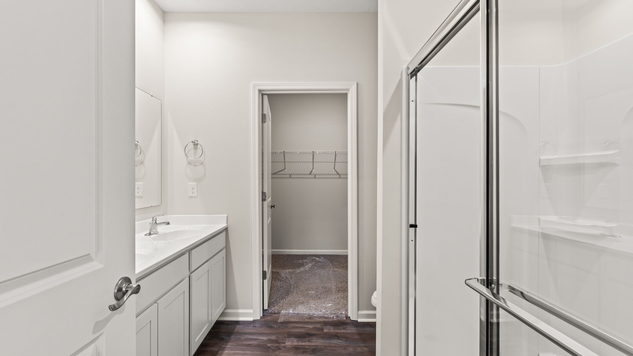 Primary bathroom with sink on the left, closet in center, and walk-in shower on right.