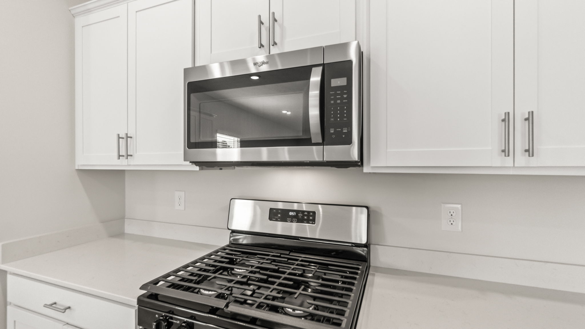 Closeup of oven range and microwave inbetween cabinetry and countertop
