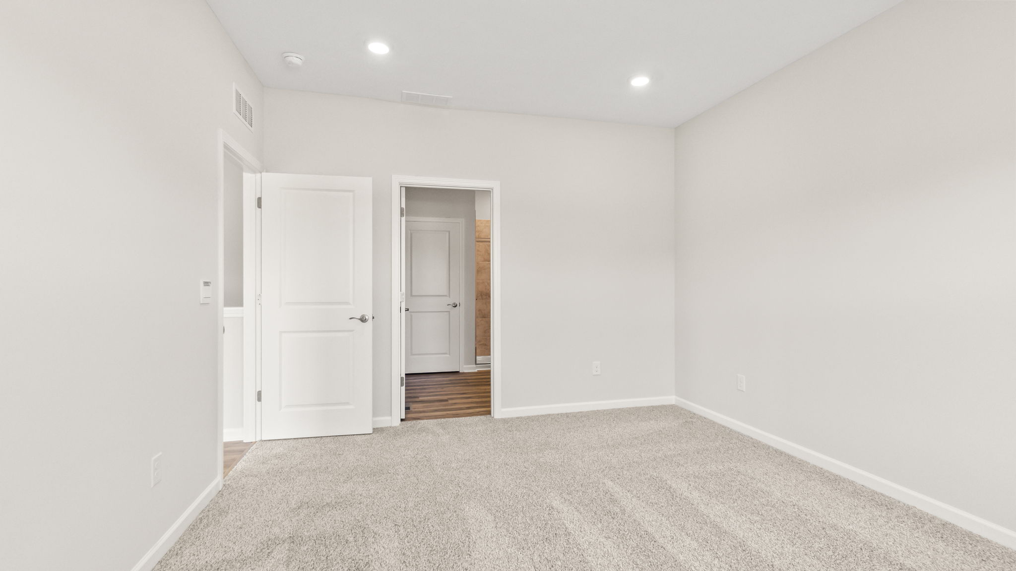 Carpeted primary bedroom with door leading to hallway