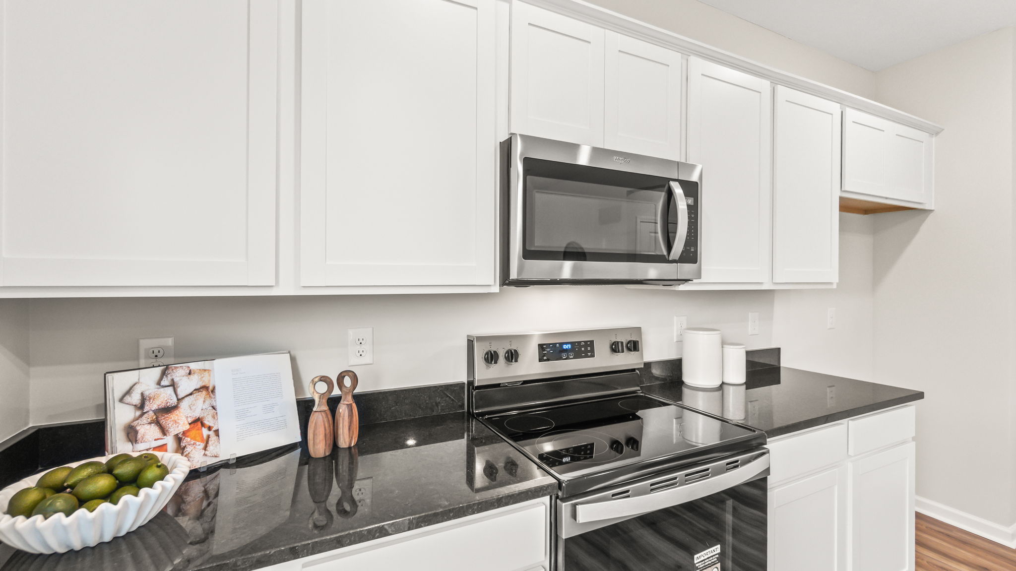 closeup of white cabinetry, oven range, and granite countertops