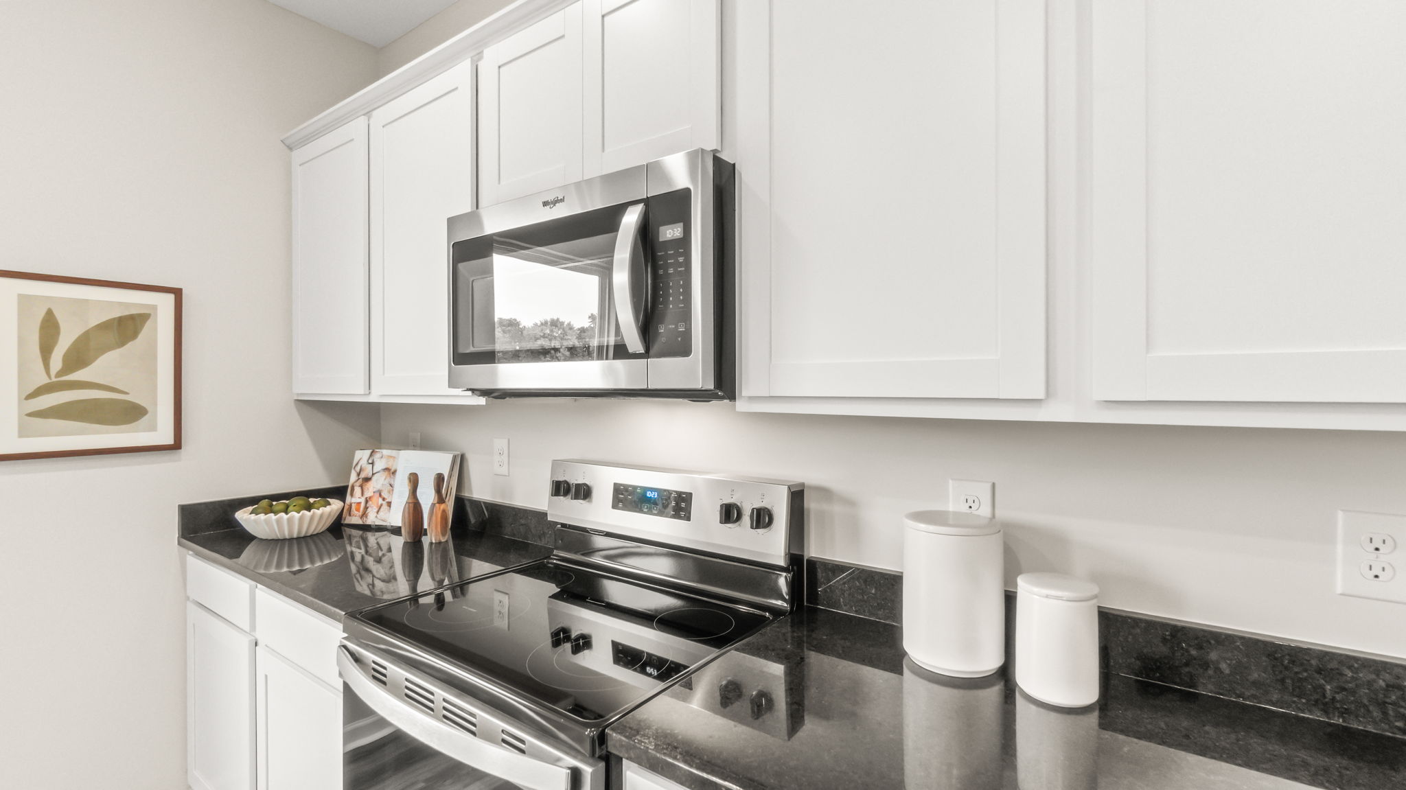 closeup of white cabinetry, oven range, and granite countertops