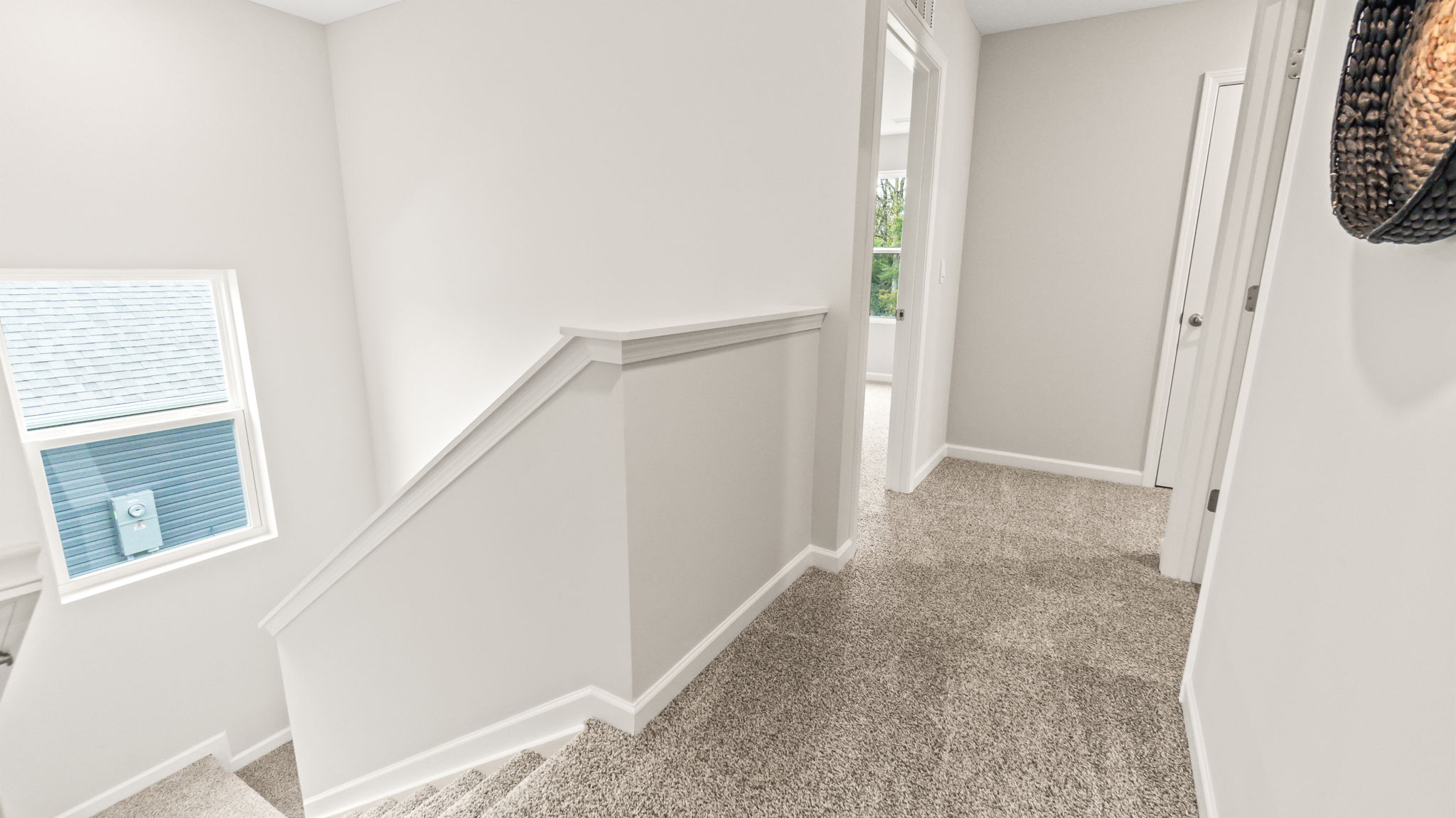 Upstairs landing with carpet and stairs leading to first floor on the left and doors to bedroom on right of frm