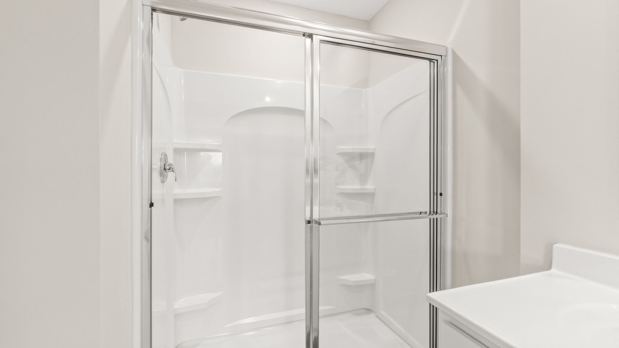 Closeup of shower with sliding glass door and tiered shelving