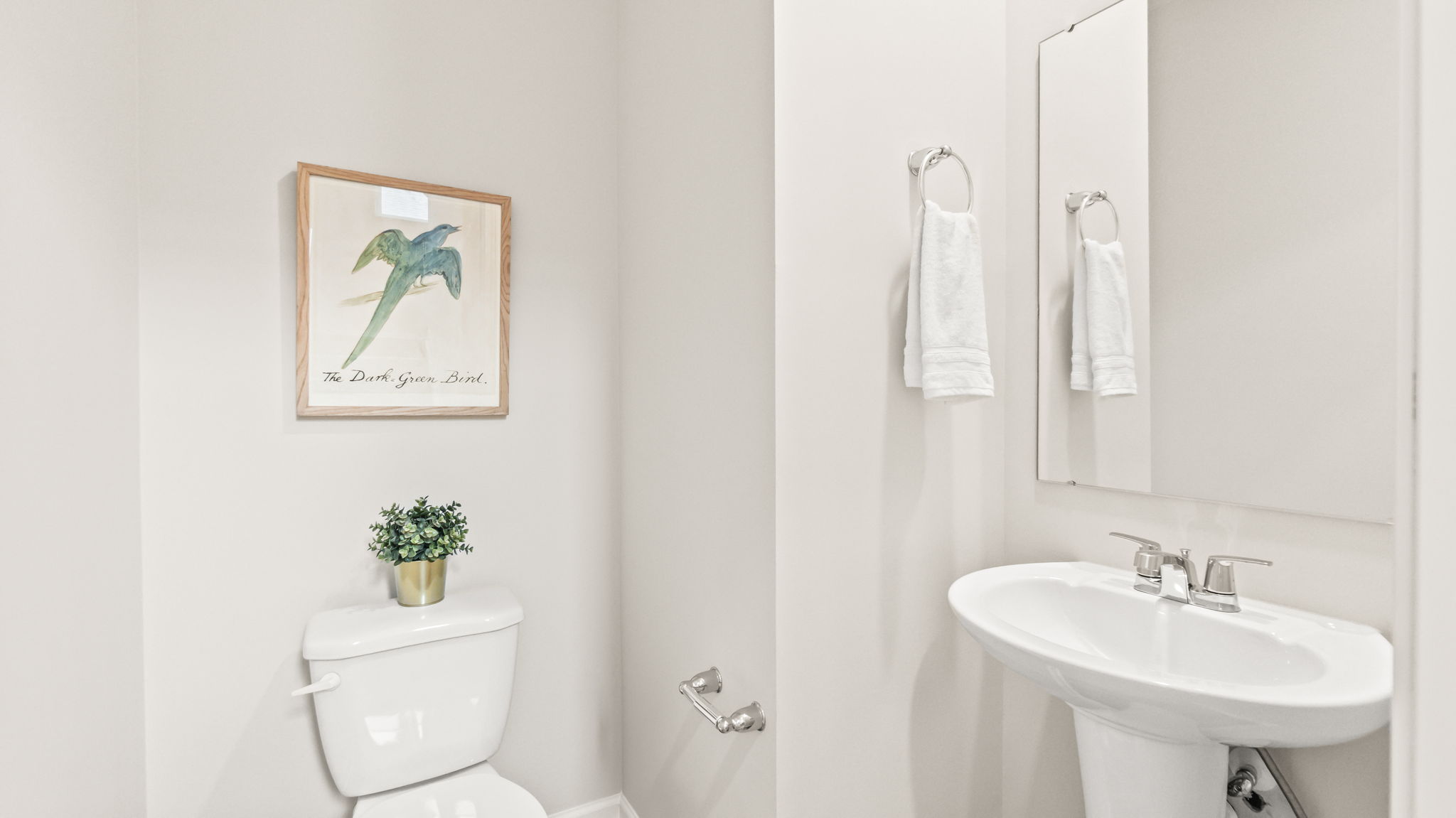 toilet room with sink, toilet, and nature themed art