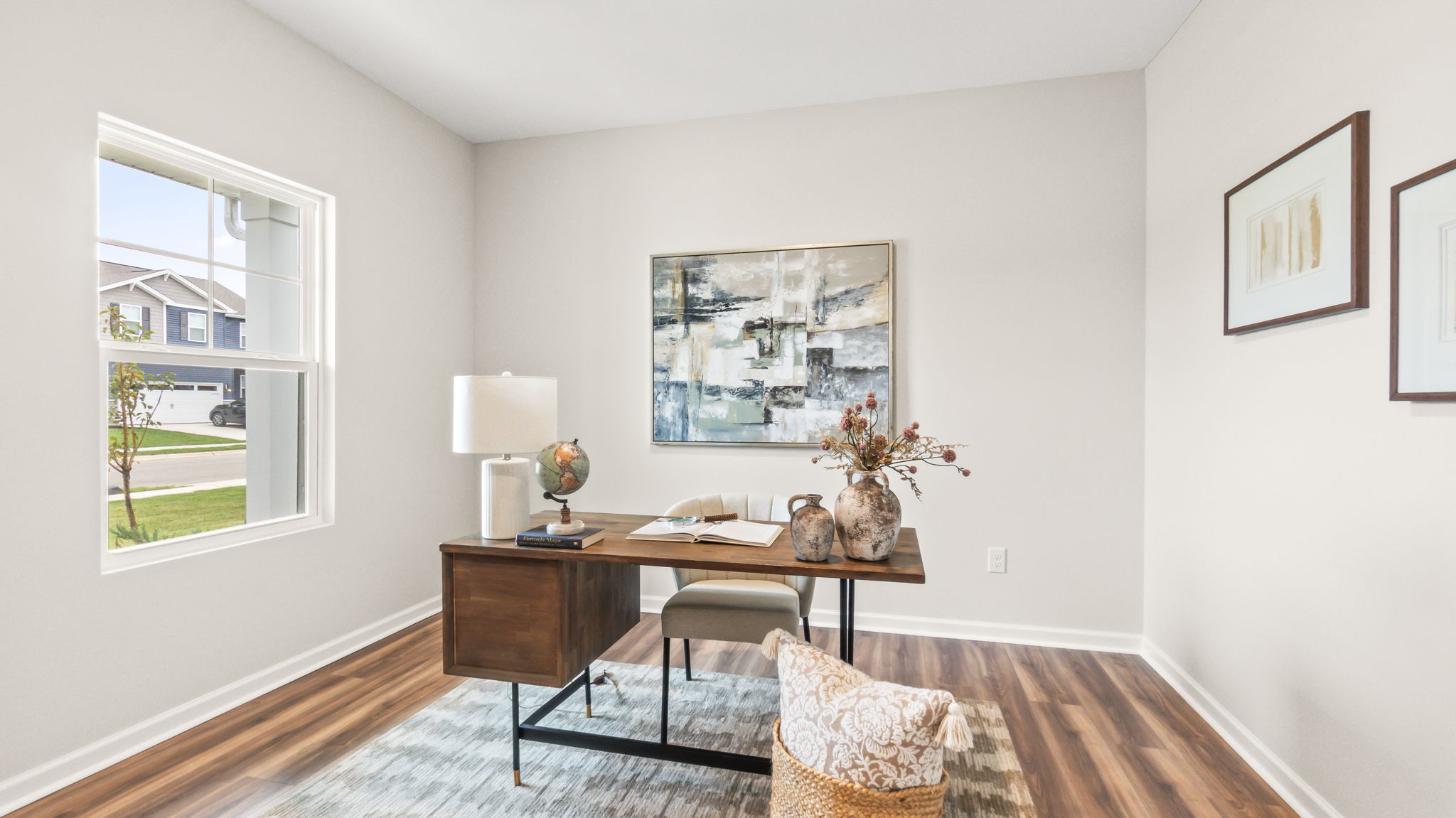 Home office with desk, two chairs, and contemporary art pieces on the wall