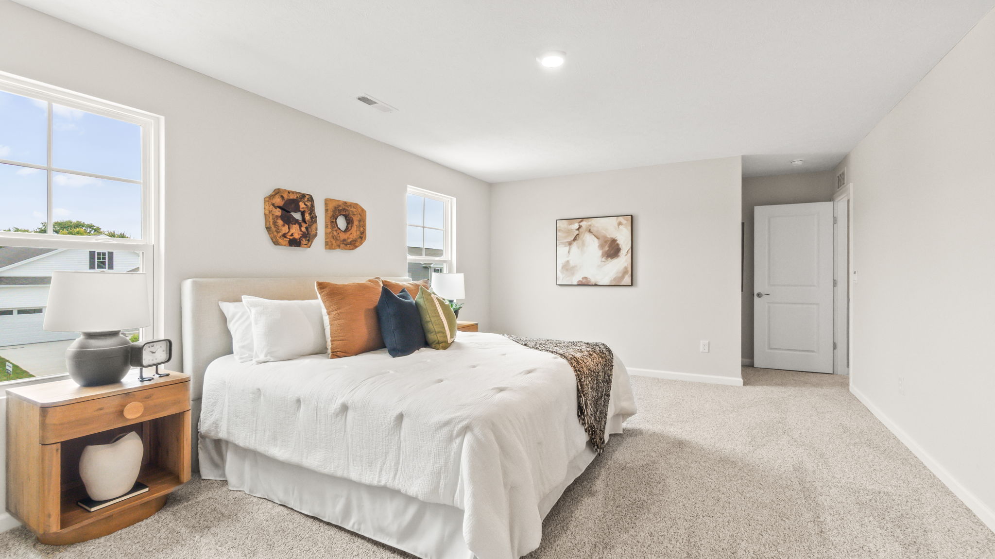 Primary bedroom with white bedding and blue/orange/white toning