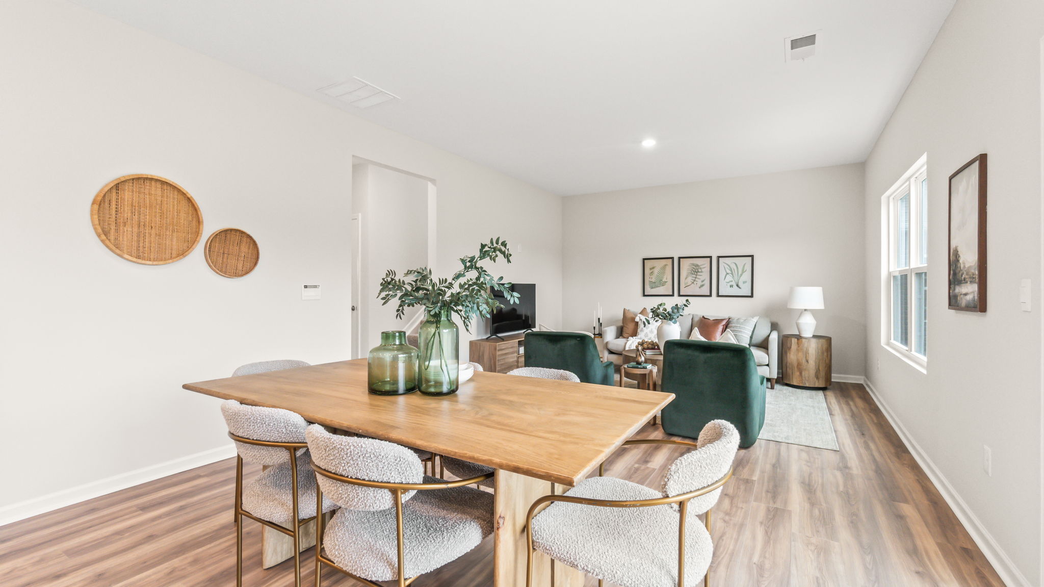dining area with wooden table, chairs, art on walls, and living room area in background