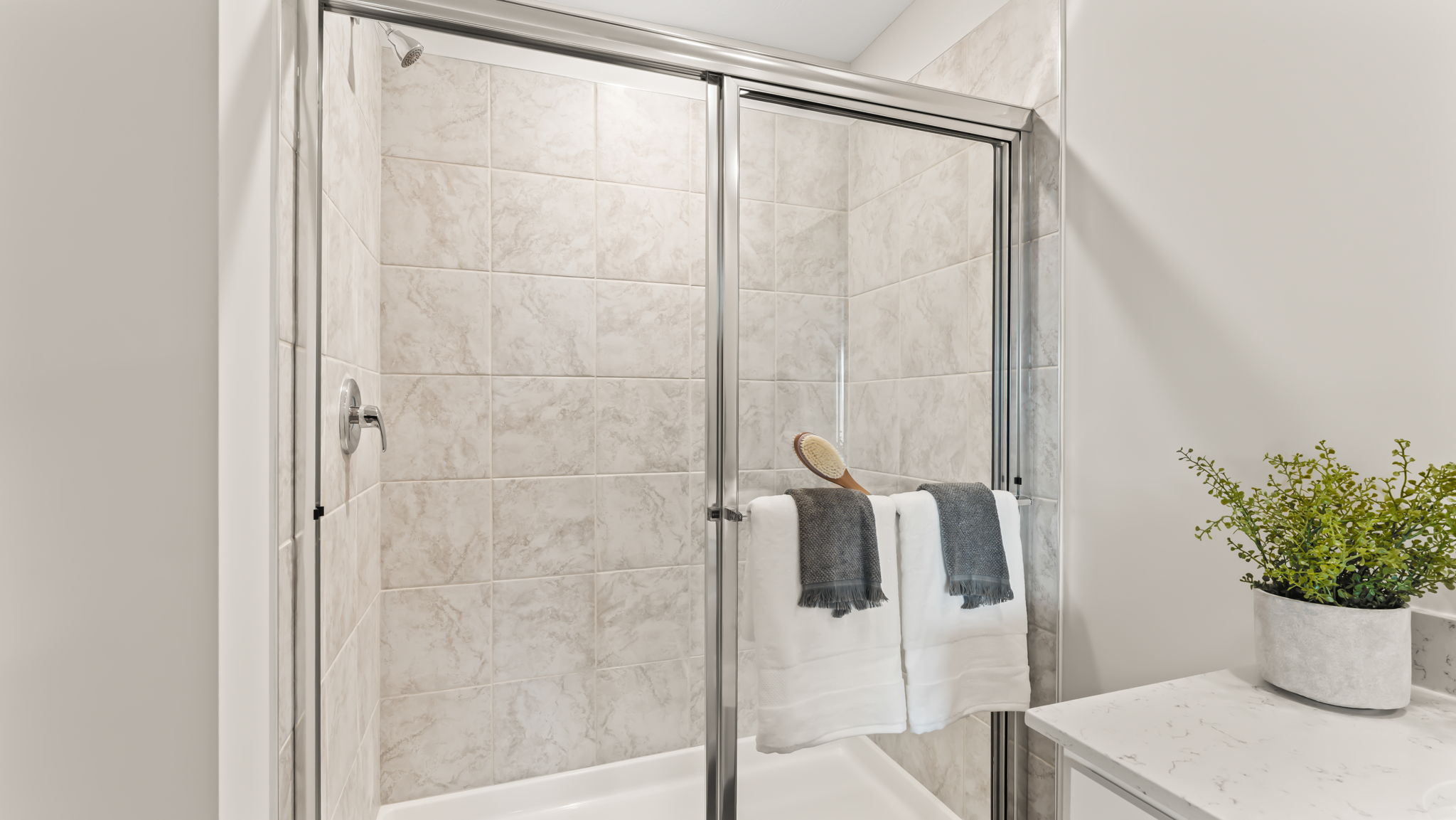 Walk-in shower with glass doors and tile wall