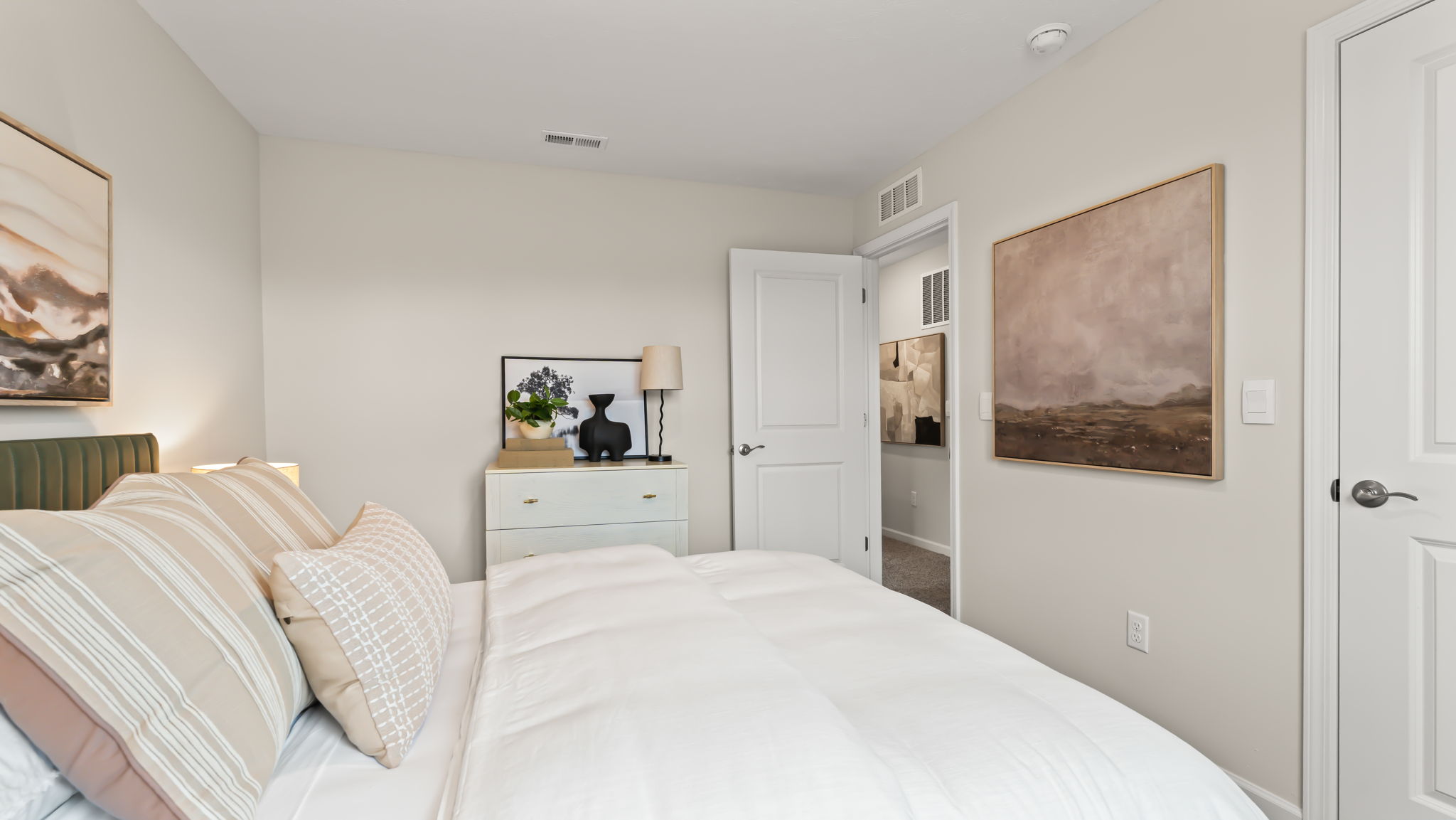Closeup of bed adjacent to white dresser drawer