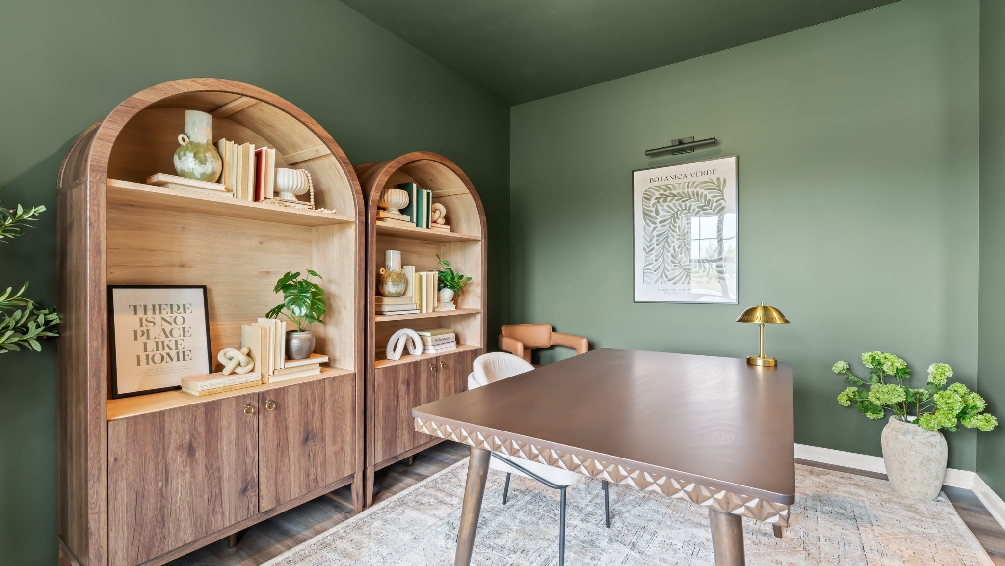 Office room with large wooden bookshelves, deep green walls, and plants in vases