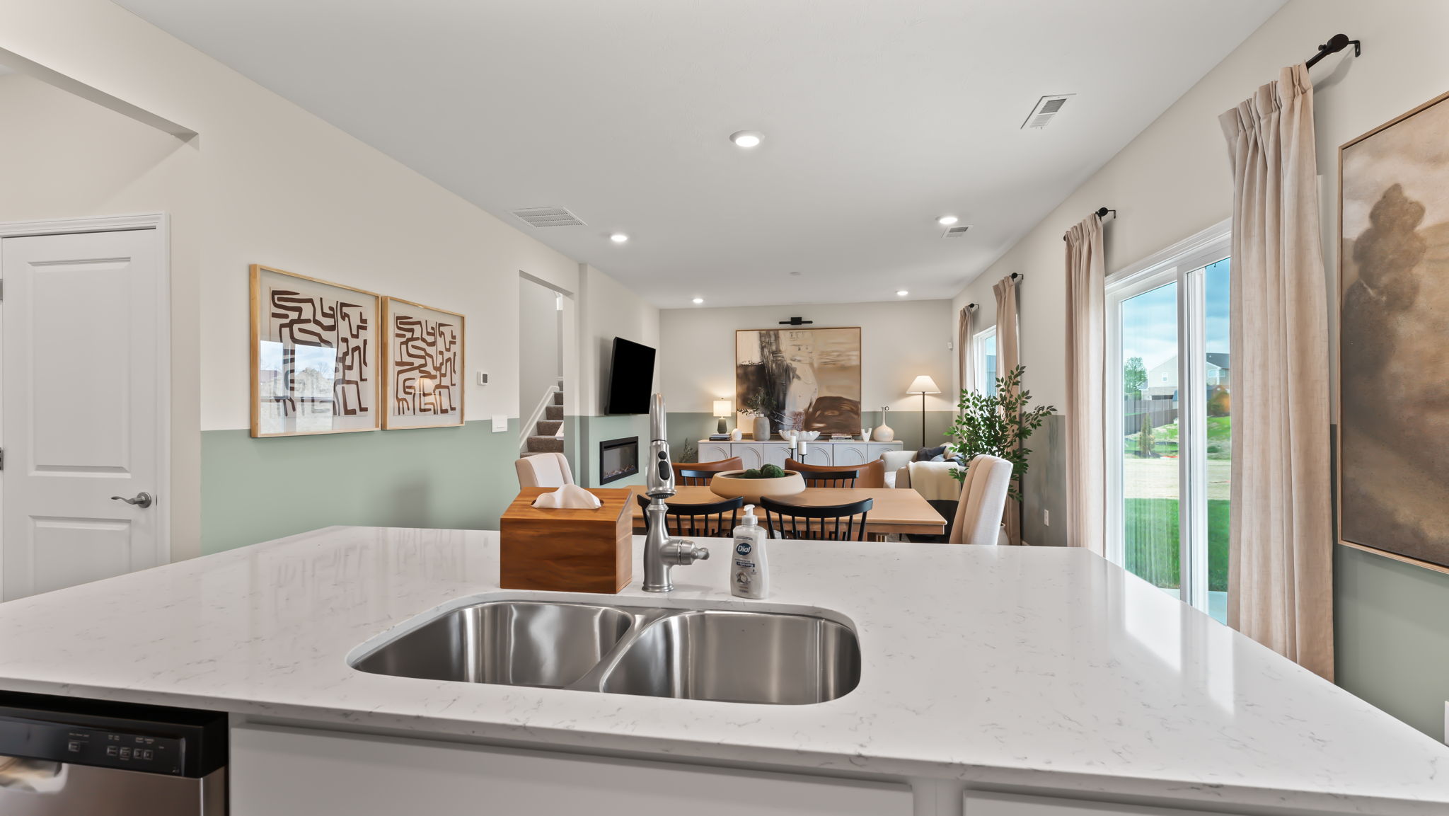 Perspective of the great room from the quartz kitchen island containing stainless steel dishwasher