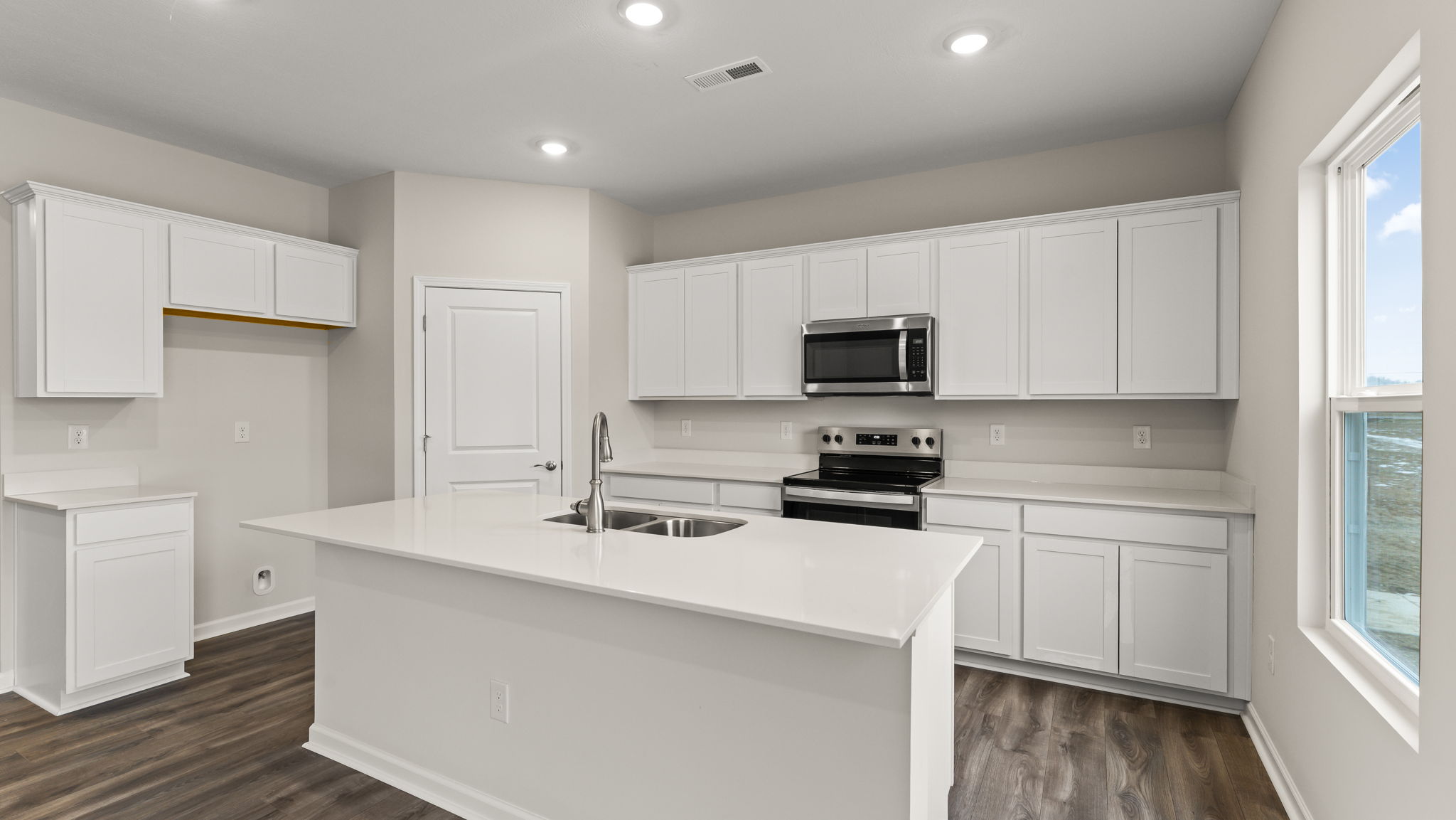 Three-quarter view of kitchen island, appliances, and white cabinetry.