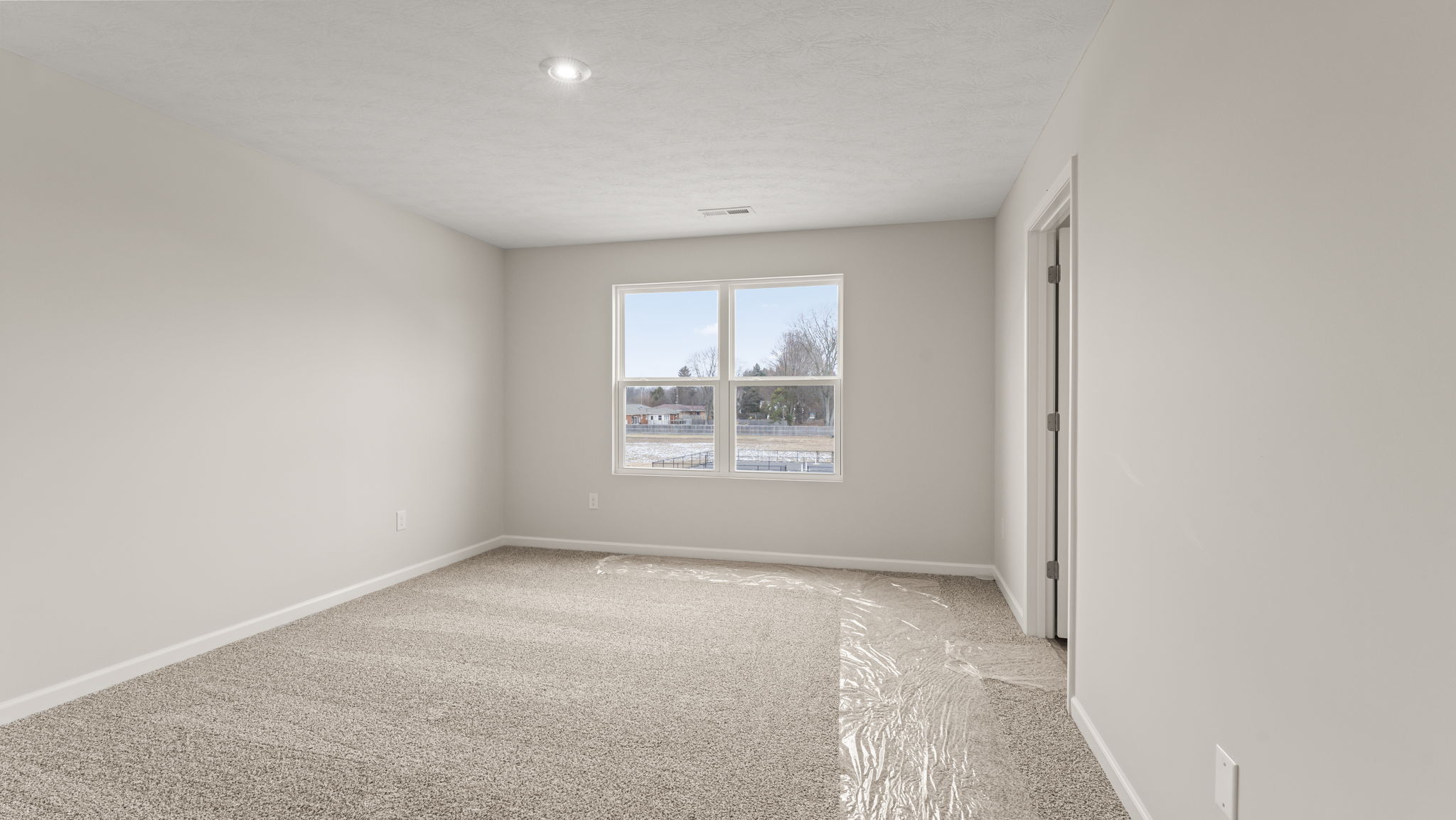 Carpeted primary bedroom with window