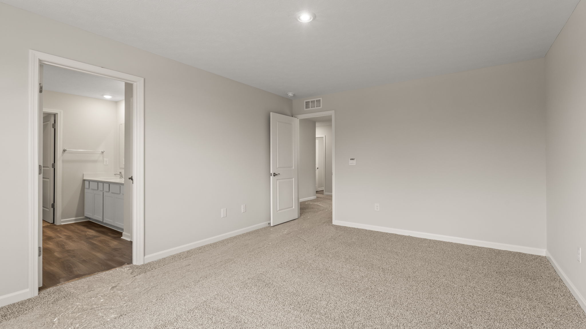 Carpeted primary bedroom with view of bathroom