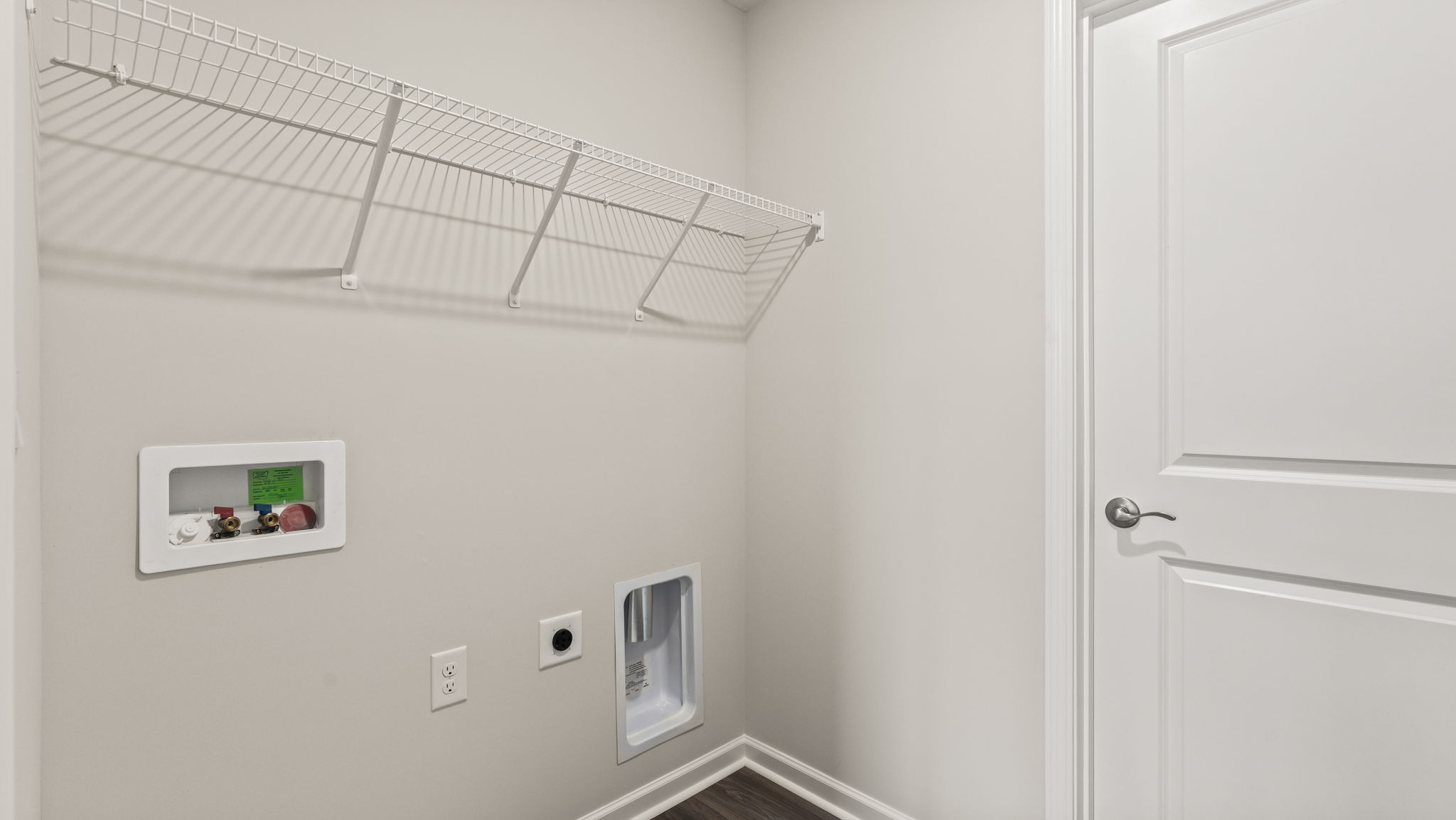 Laundry area with wire rack shelving and washer/dryer inlets