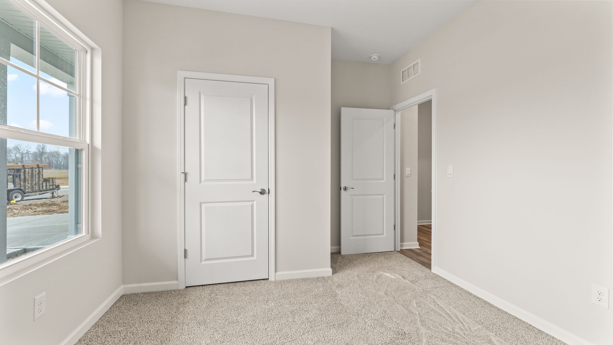 Carpeted bedroom with window, closet, and view of hallway through door