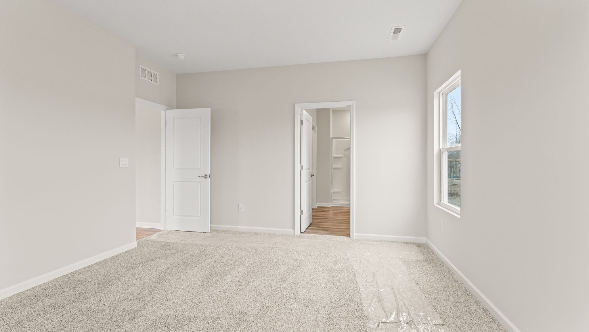 Primary bedroom with view of primary bathroom suite