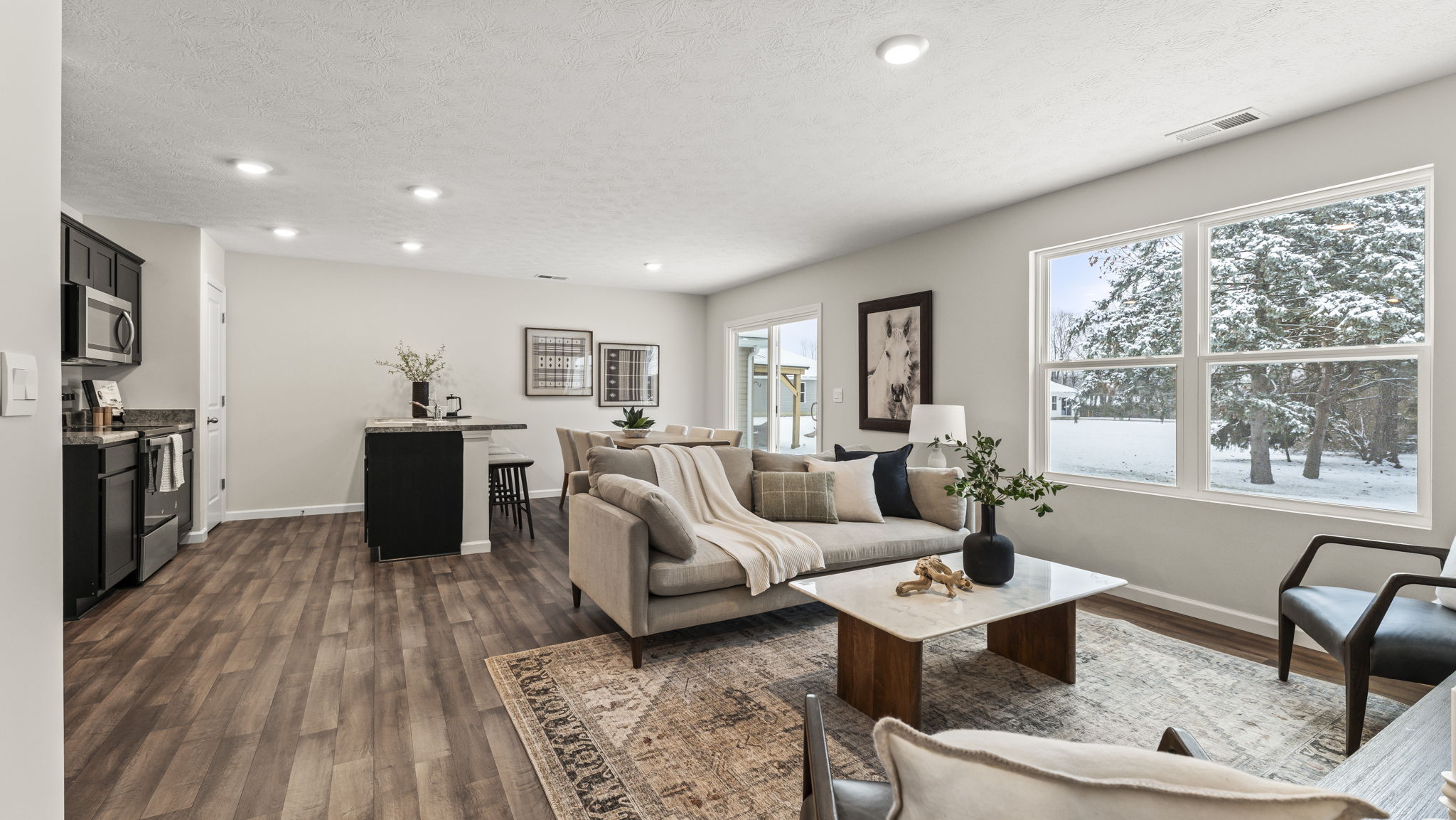 Living room looking toward dining and kitchen areas with natural light and smooth open-concept flow