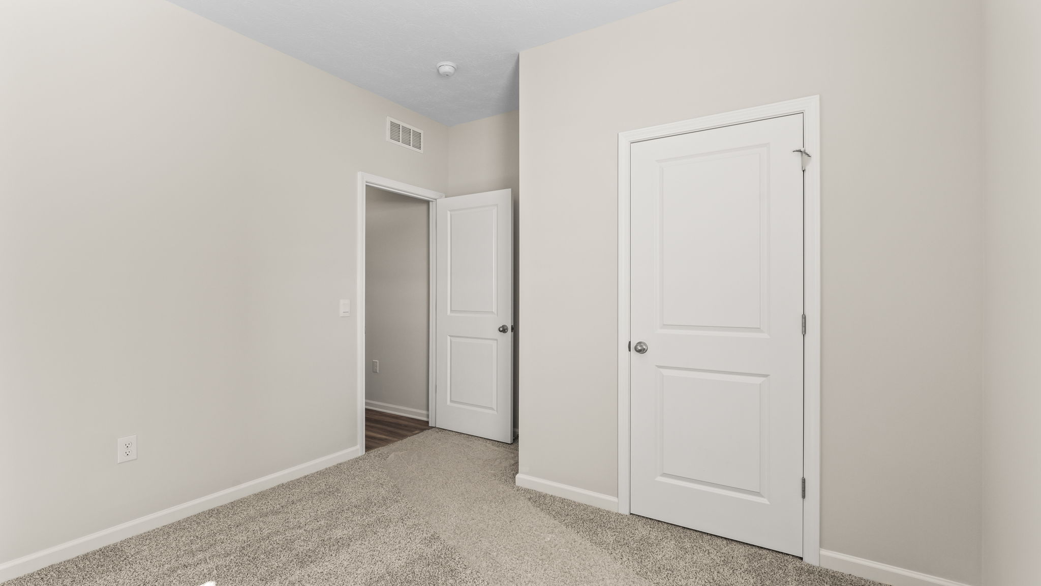 Carpeted bedroom with doors leading to the closet and hallway