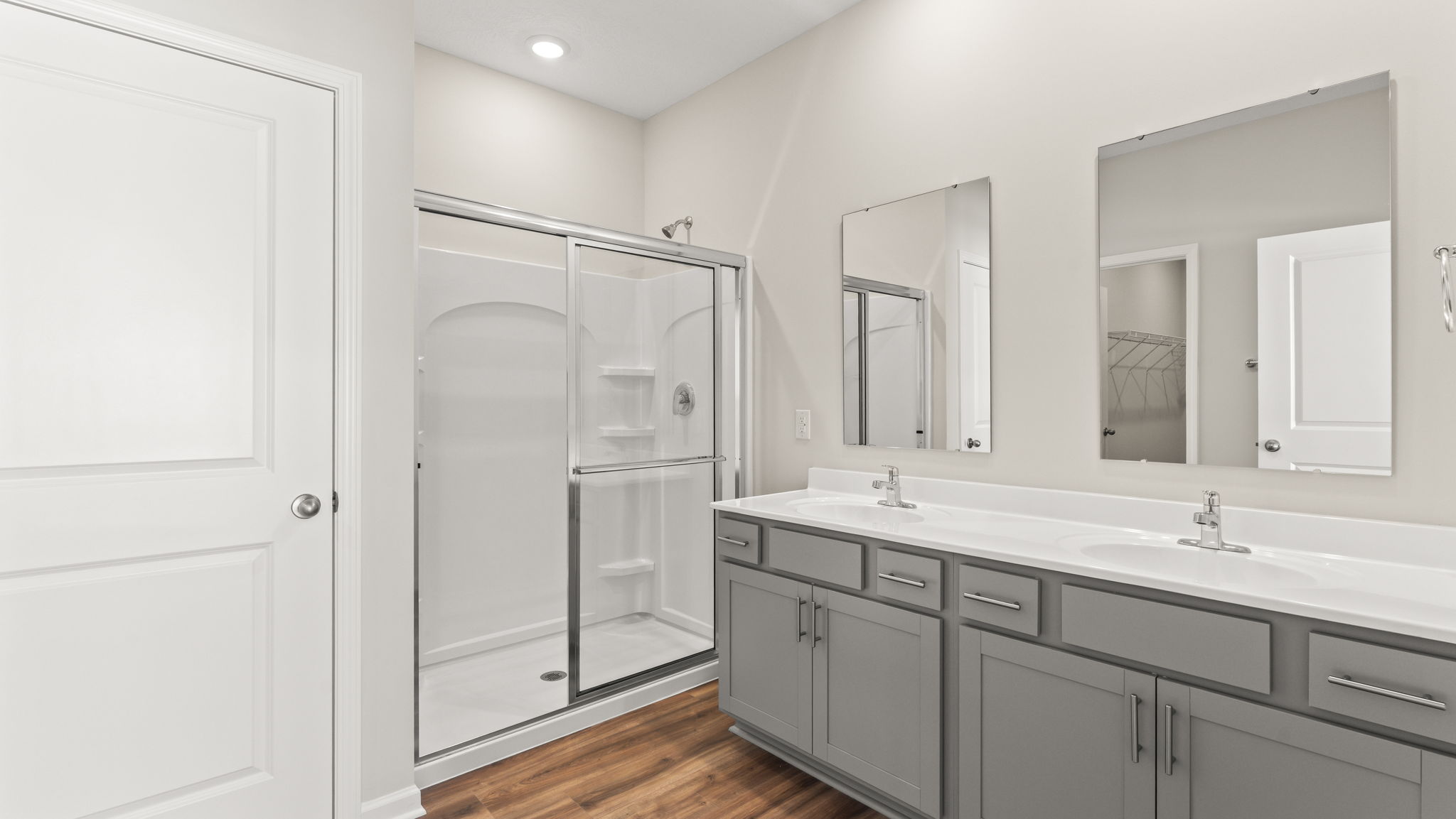 Primary bathroom with gray cabinetry, dual-sink vanity, and walk-in shower.