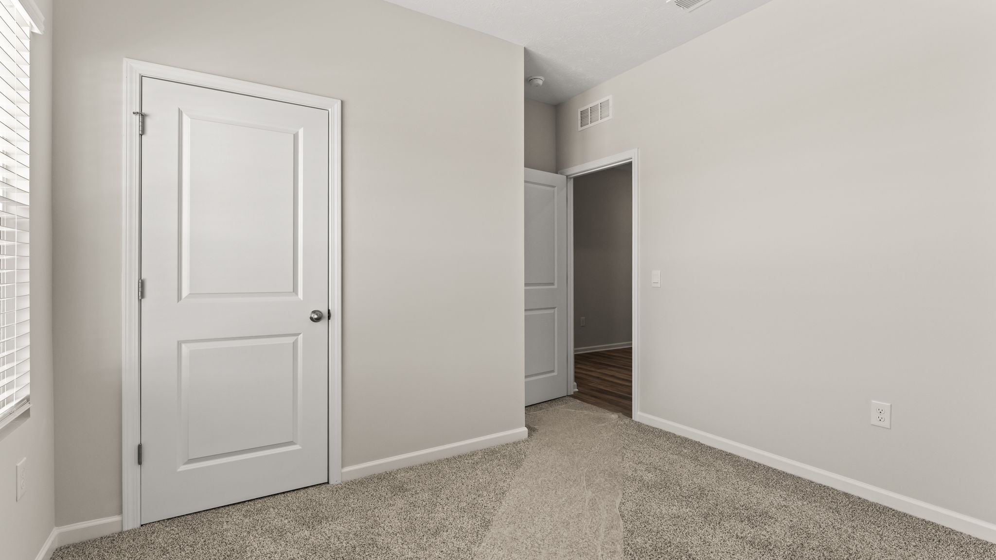 Carpeted bedroom with doors leading to the closet and hallway