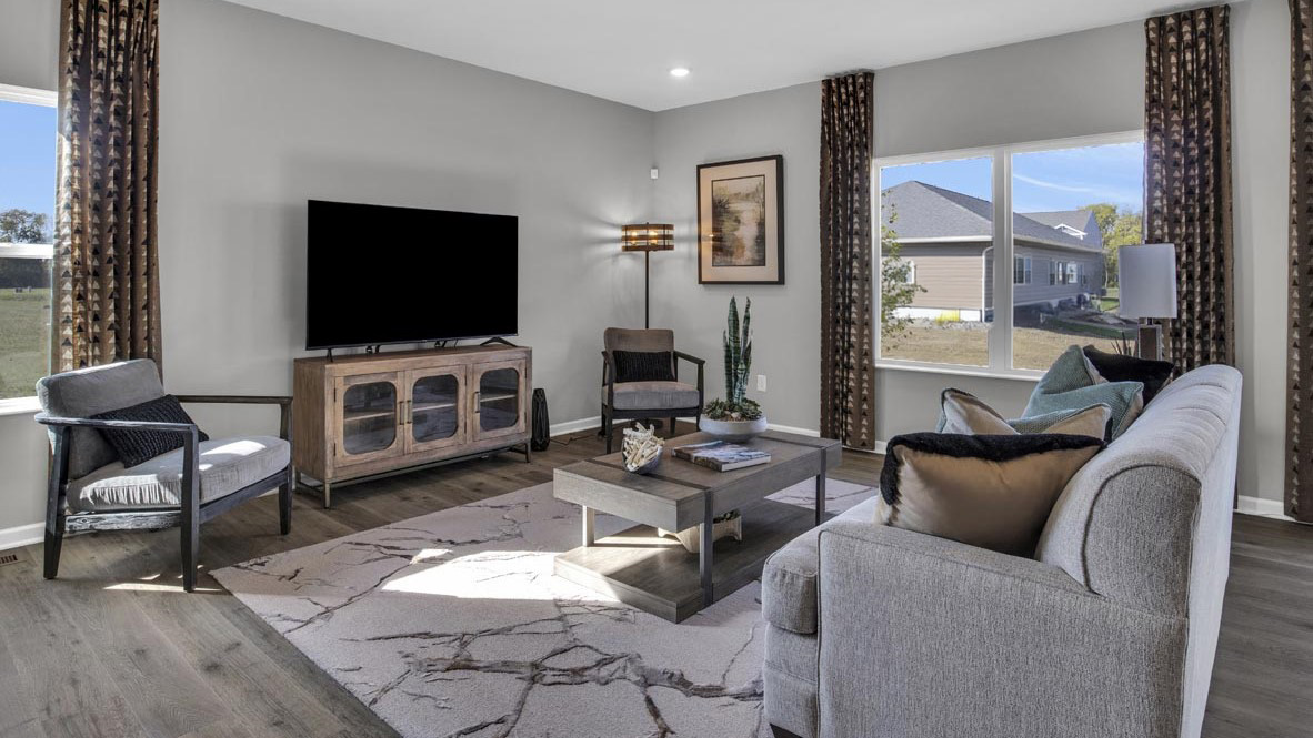 Full living room with modern carpet, lush grey couch, comfortable seating, and modern art.