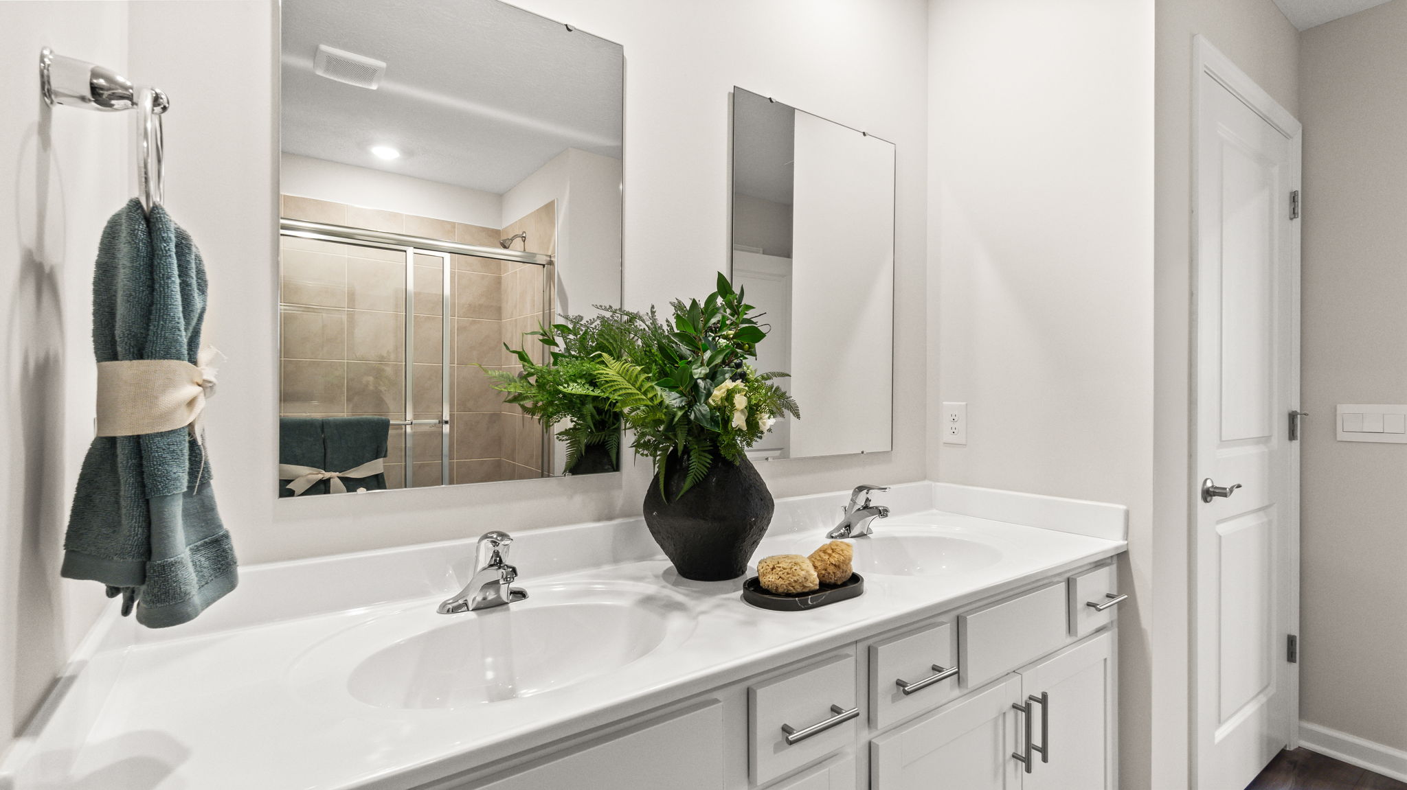 Closeup of cultured marble, dual-sink and mirror, and hanging hand-towel.