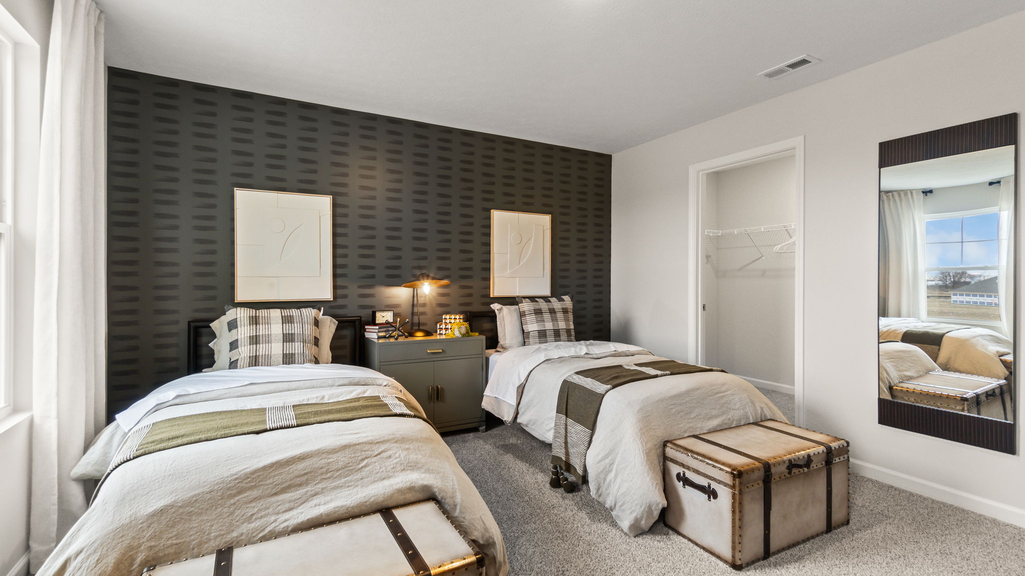 Bedroom 2 with twin beds, nightstand with lamp, storage trunks, mirror, and storage closet with wire shelving.