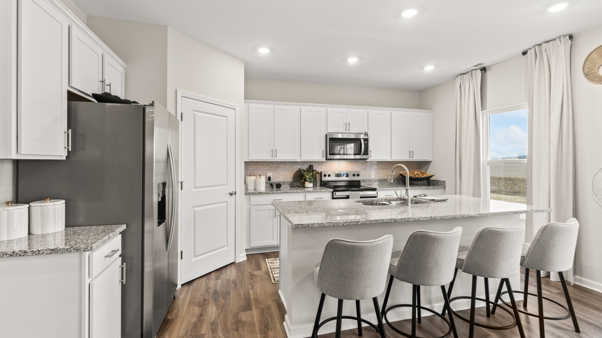 Three-quarter perspective of kitchen with granite counterops, appliances, and white elkins cabinetry.