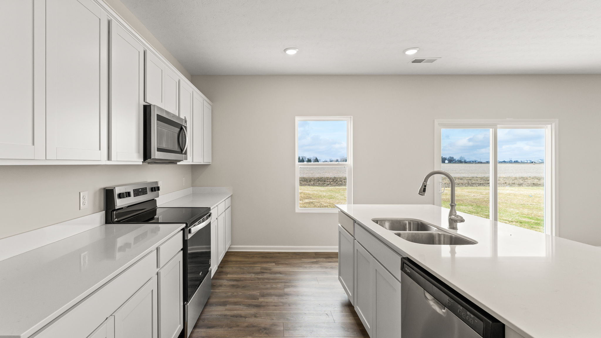 Side view of kitchen with appliances on left and island with dishwasher and sink on the right.