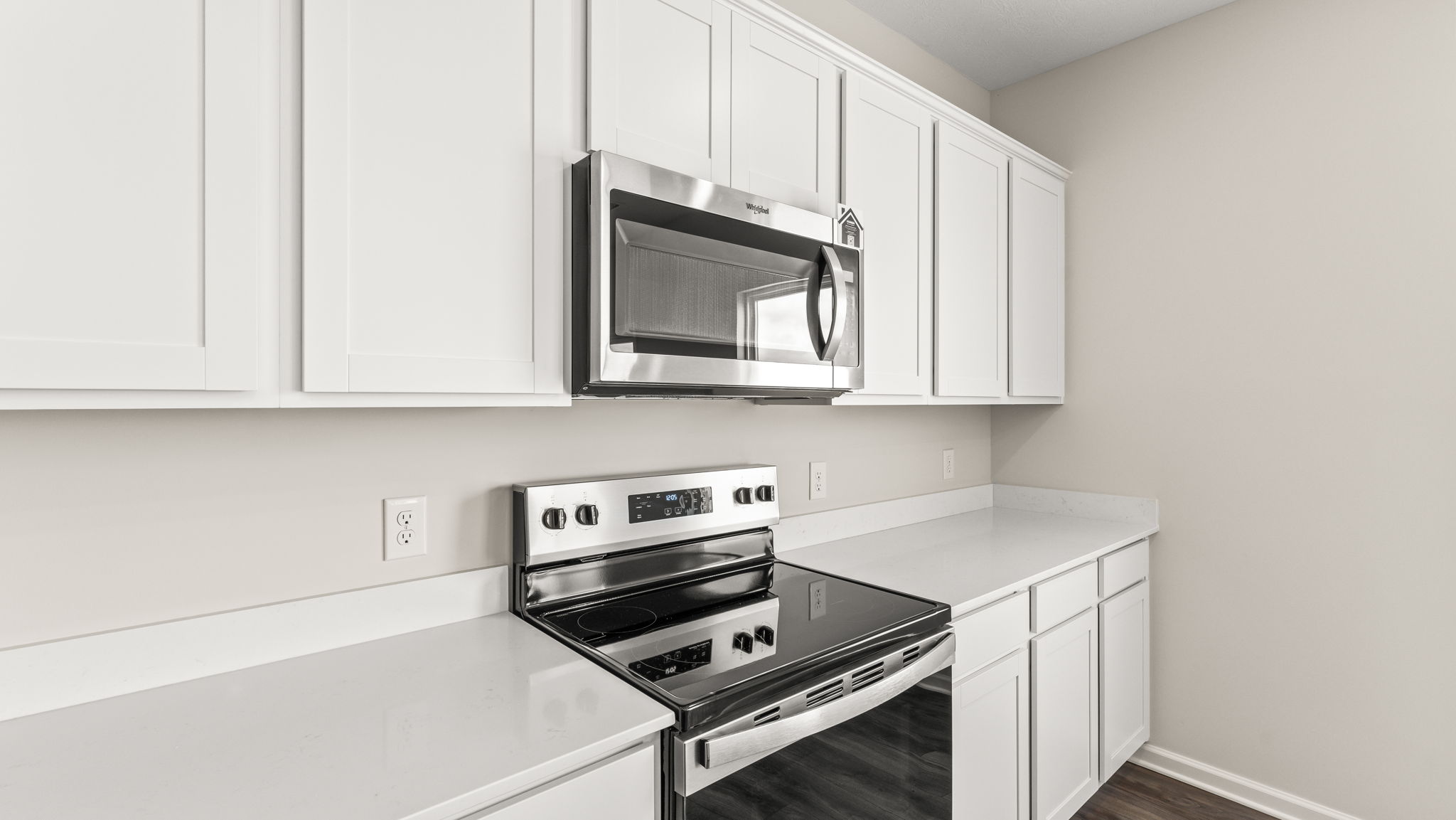Closeup of oven range between white cabinetry and quartz countertops.