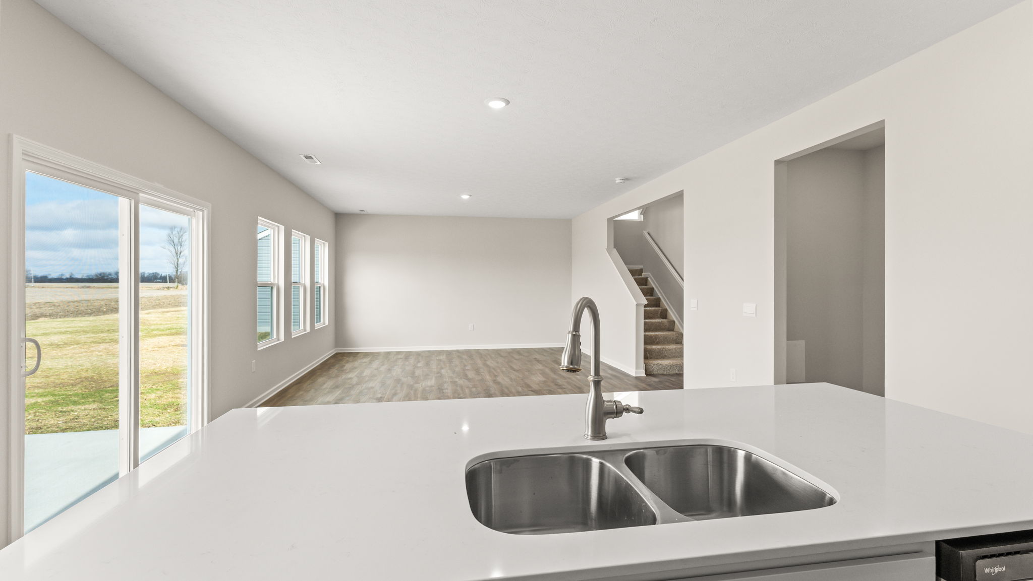 Point-of-view shot of the living room from the kitchen with quartz-top island in view.