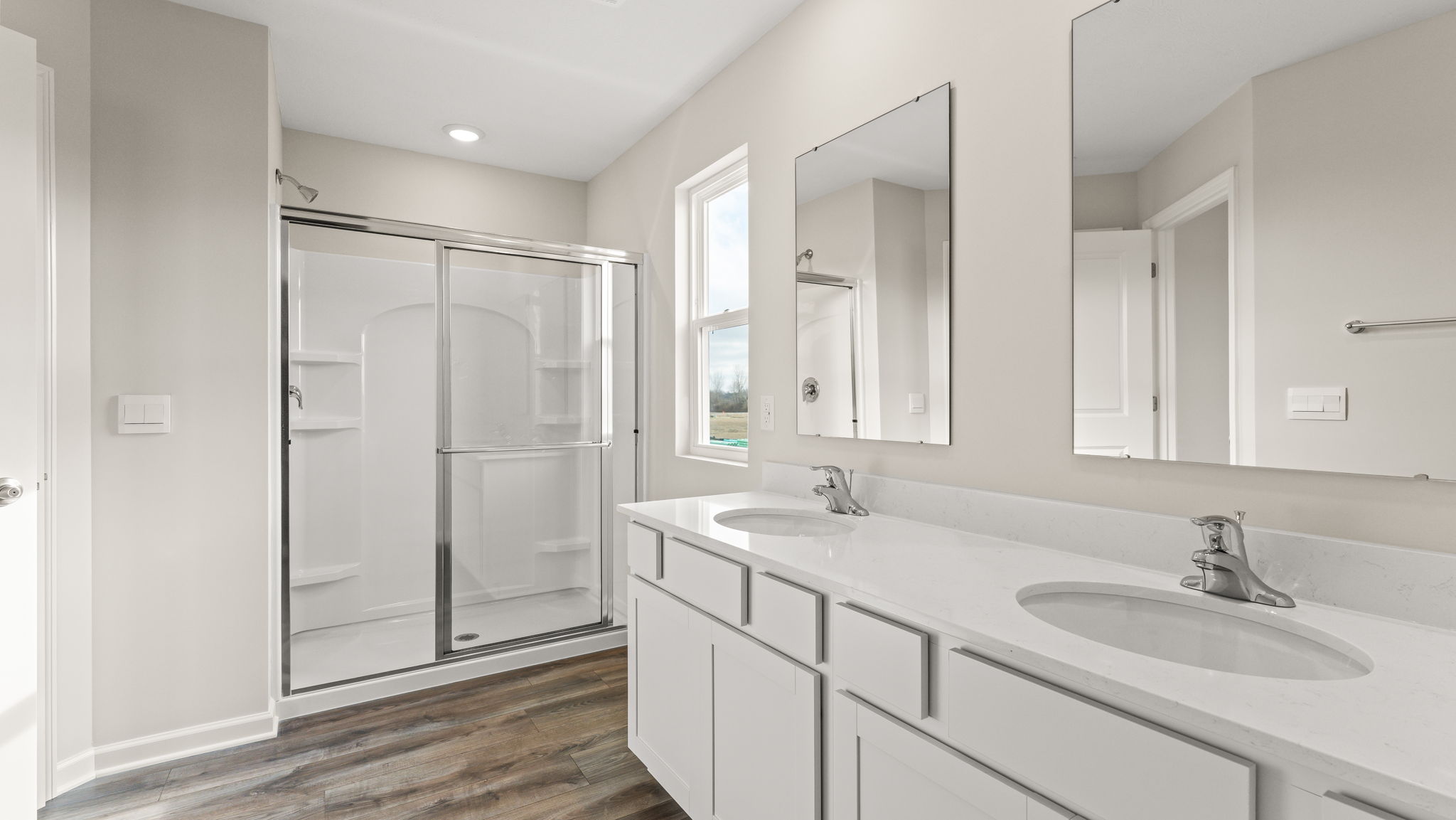 Primary bathroom with walk-in shower on the left and dual-vanity sink on the right.