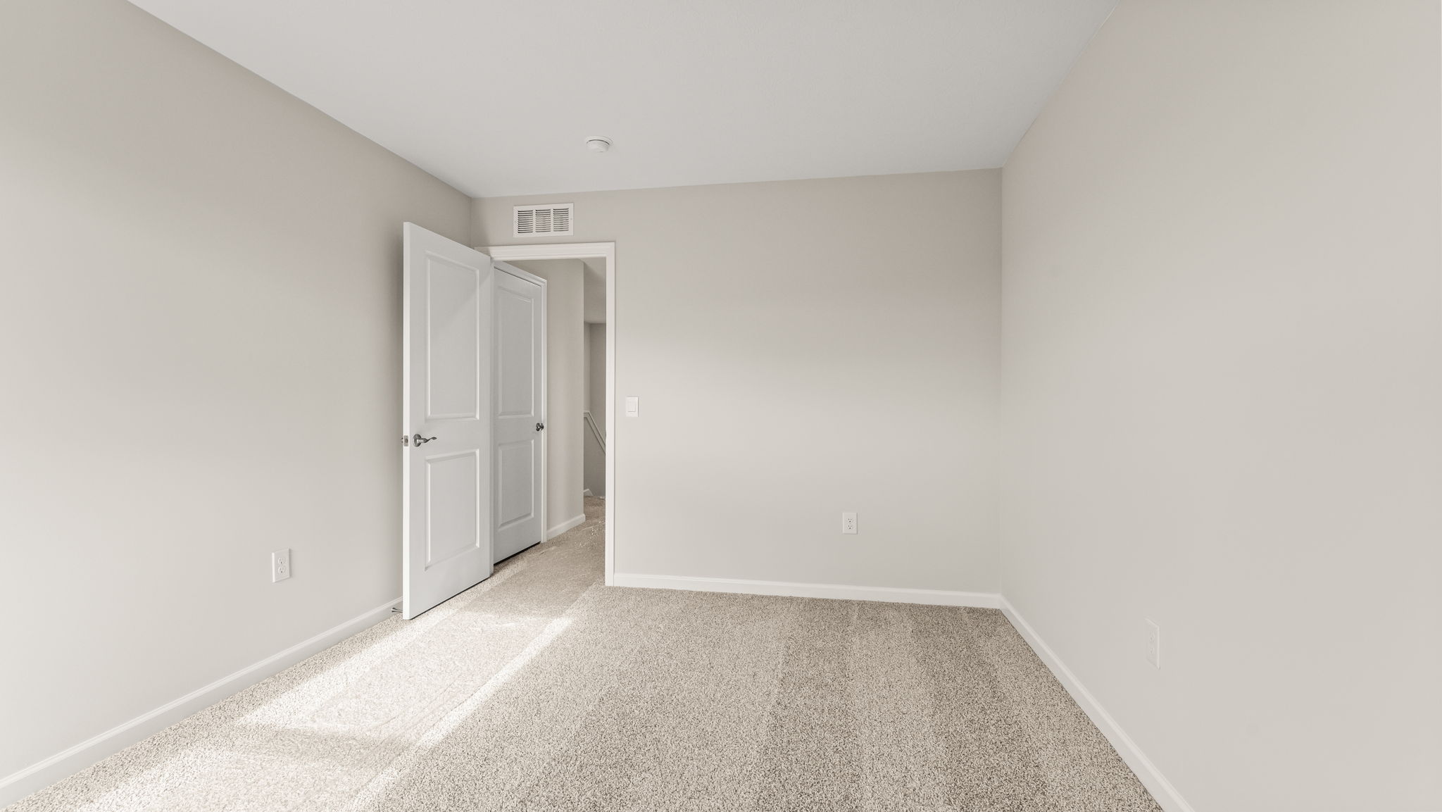 Bedroom with carpet and hallway in frame.
