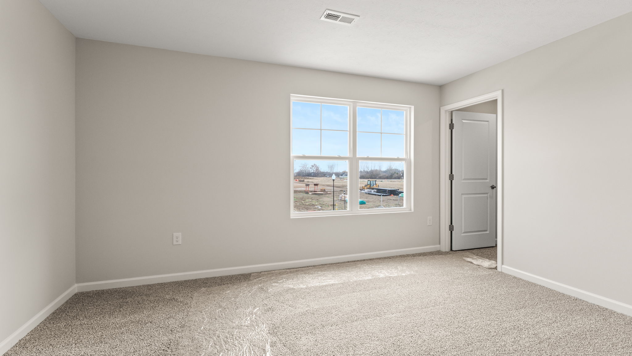 Open bedroom with walk-in closet and window.