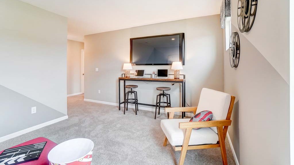 view of loft with dual barstool desk set up and large tv.