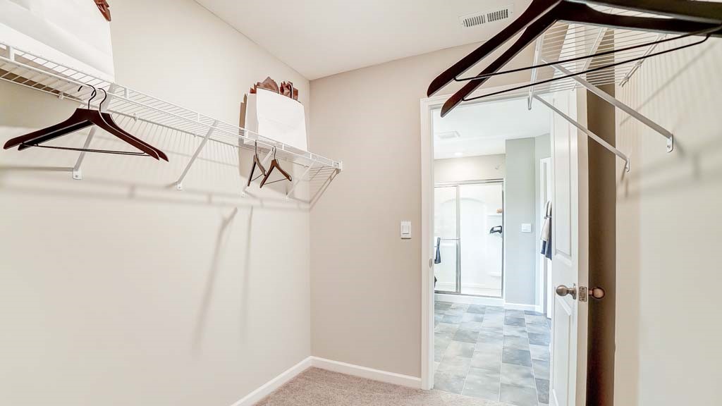 walk in closet with view into the primary bathroom.