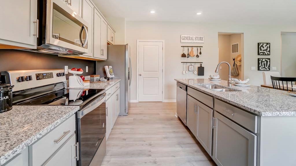 shotgun view of the kitchen with granite countertops and stainless steel whirlpool appliances and view of mud room.