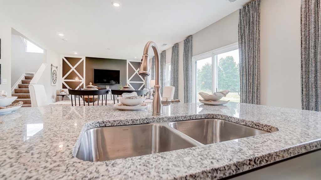 Close up of kitchen sink and great room in the background.
