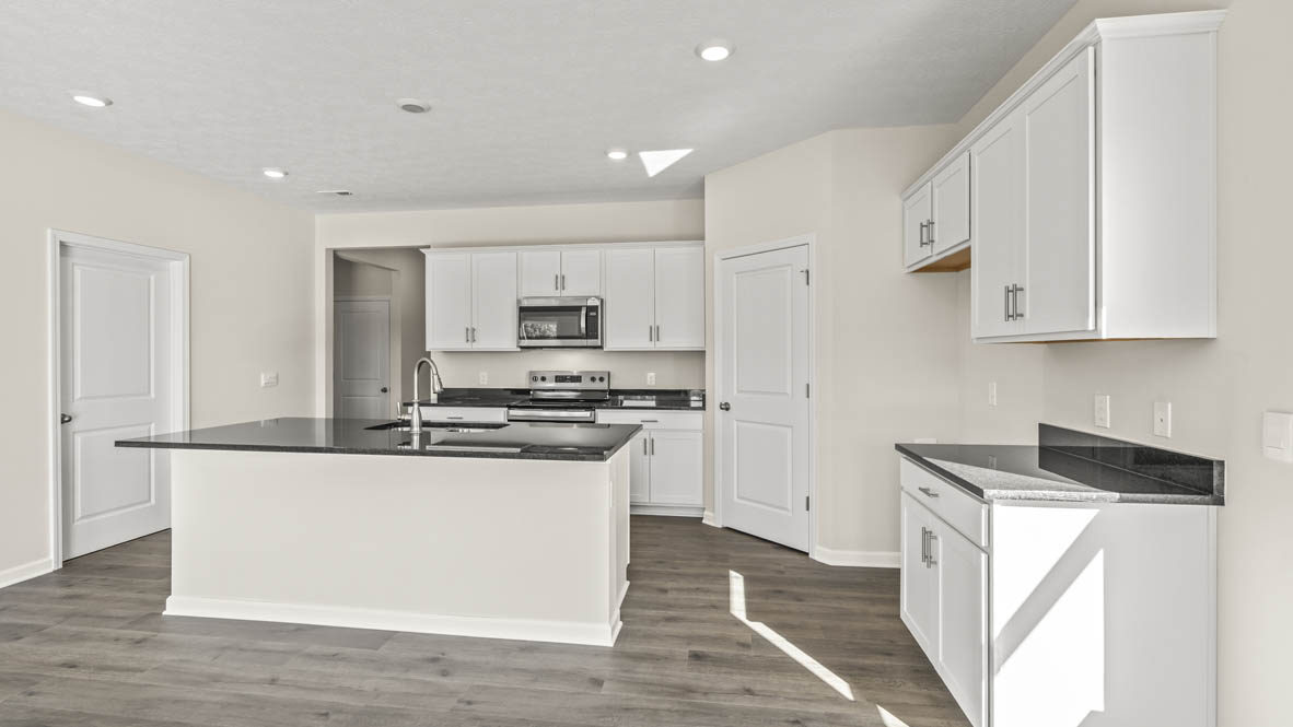 View of kitchen with white cabinetry and pantry door.